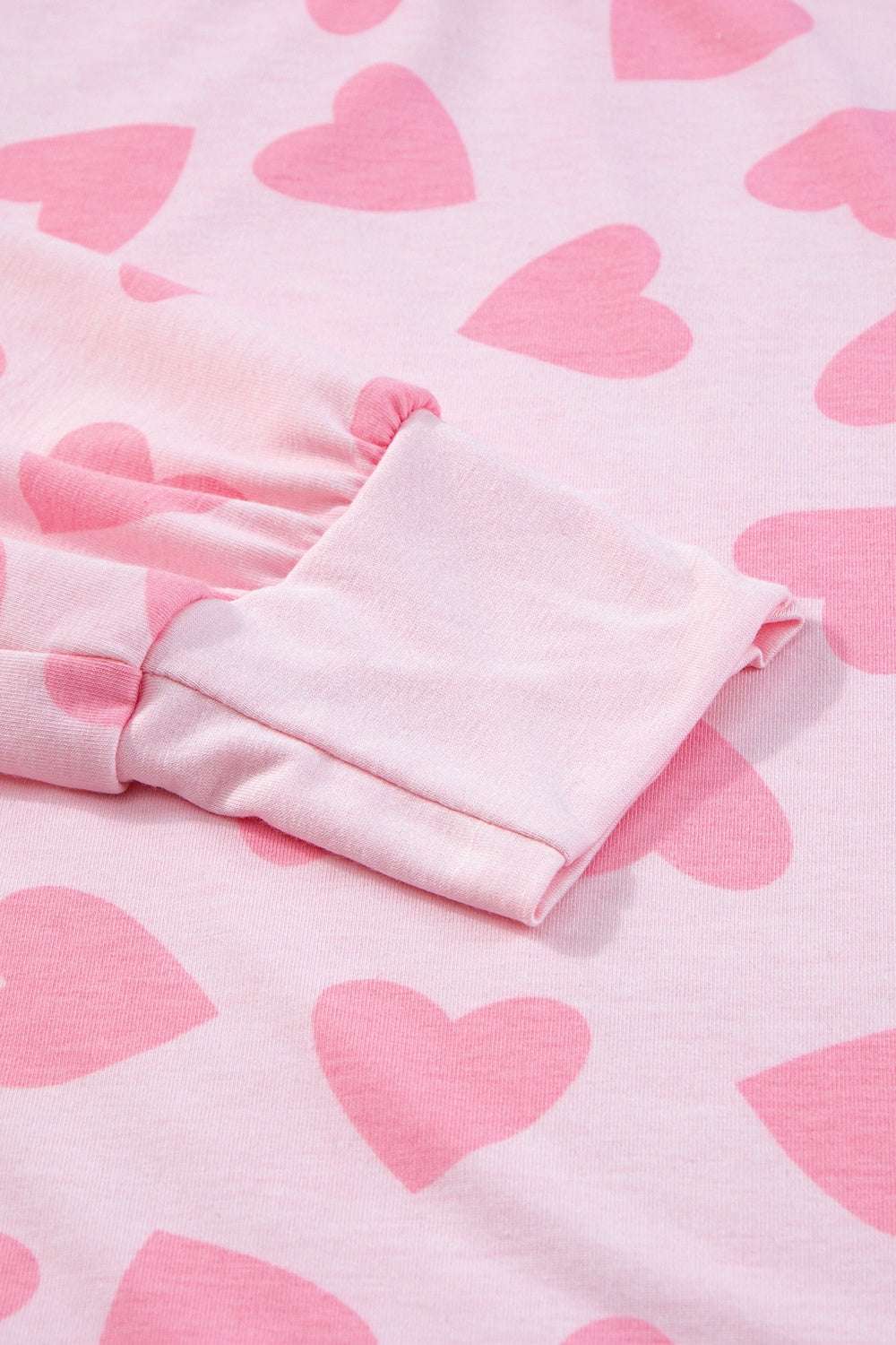 Pink heart print fabric with round neck and sleeve detail.