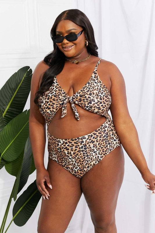 Leopard print cutout one-piece swimsuit with plunge neckline, modeled by a woman wearing sunglasses.