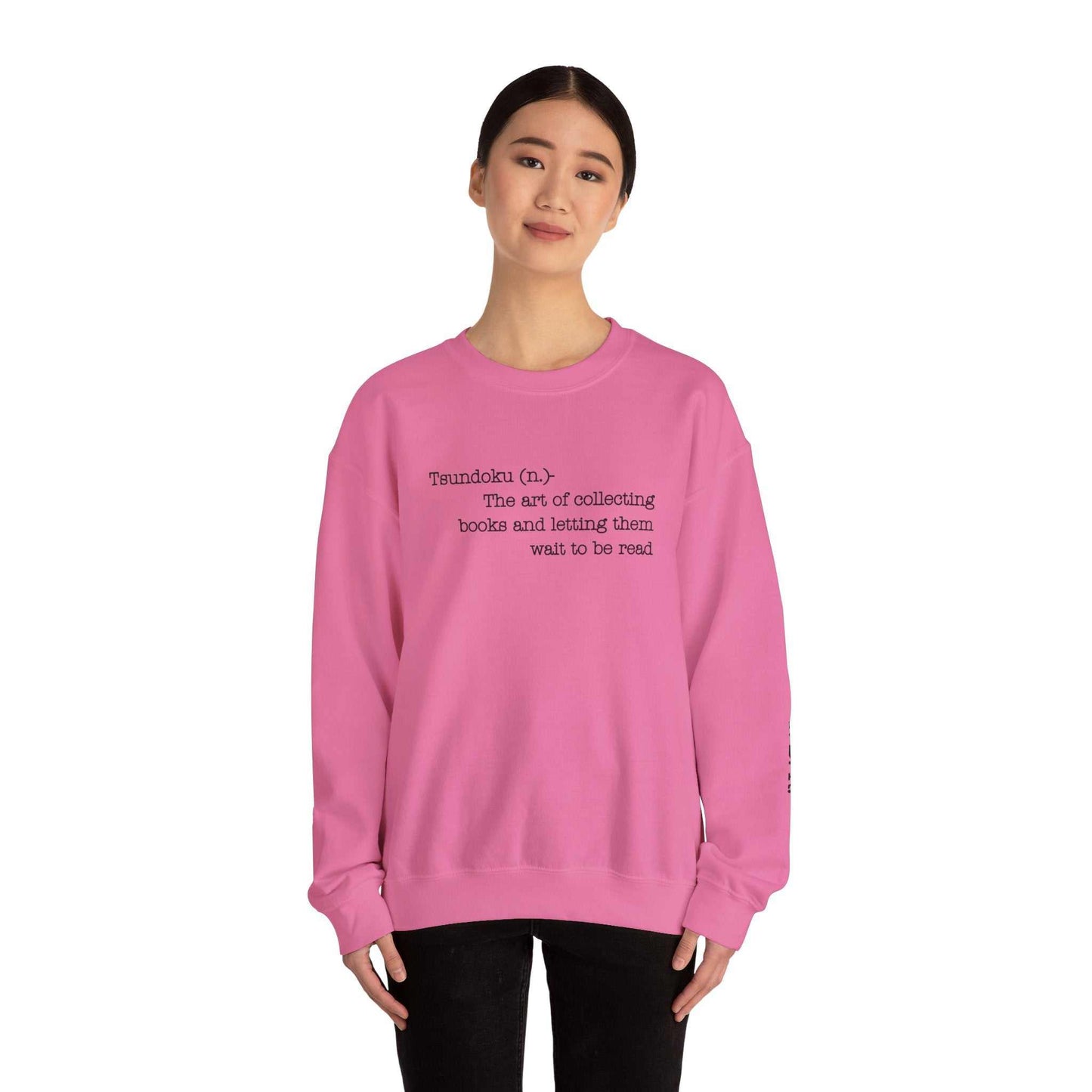 Pink "T. B. R. Tsundoku" crewneck sweatshirt displaying the definition of Tsundoku for avid readers, featuring cozy fabric and durable stitching.