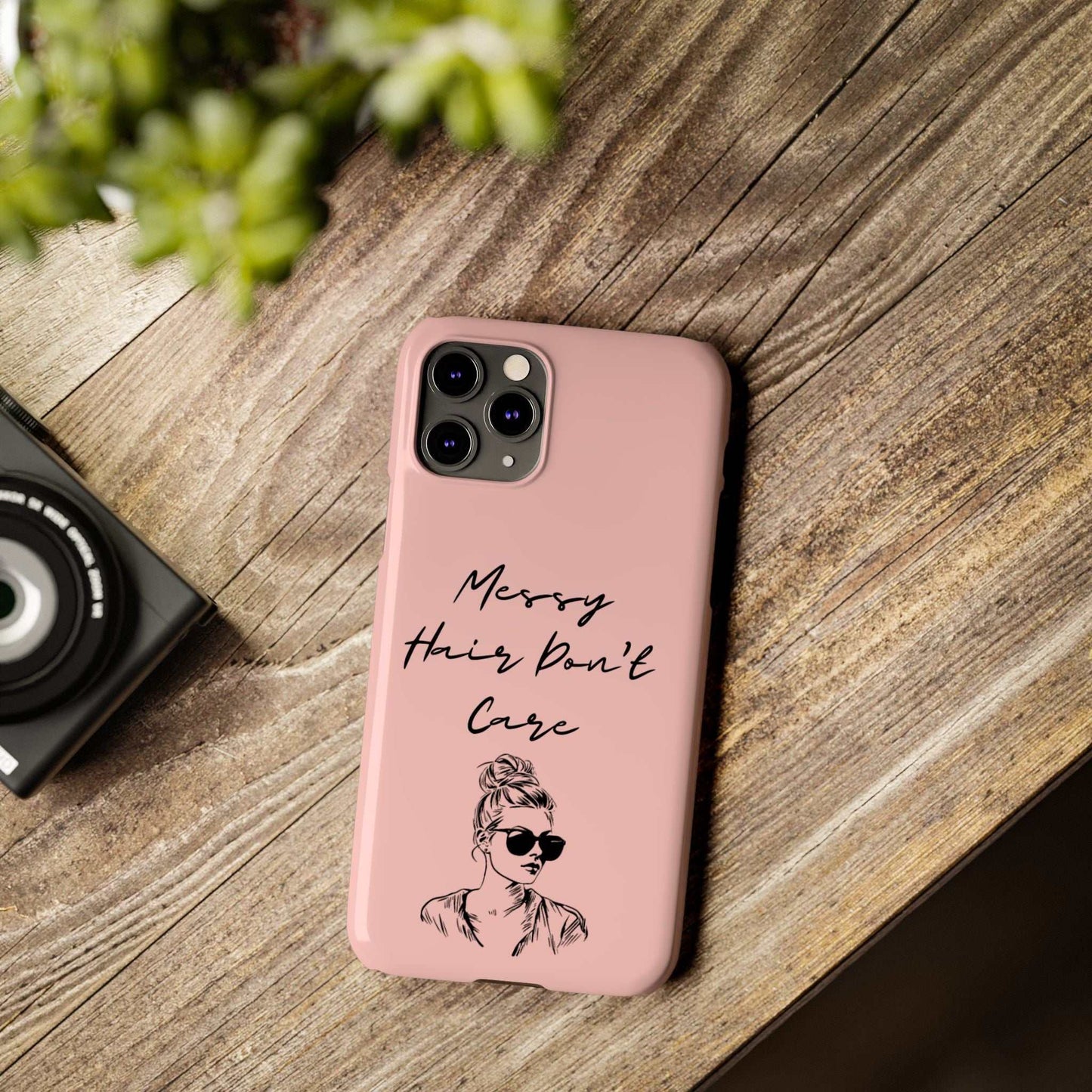 Baby pink phone case with "Messy Hair, Don't Care" and girl illustration on wooden table.