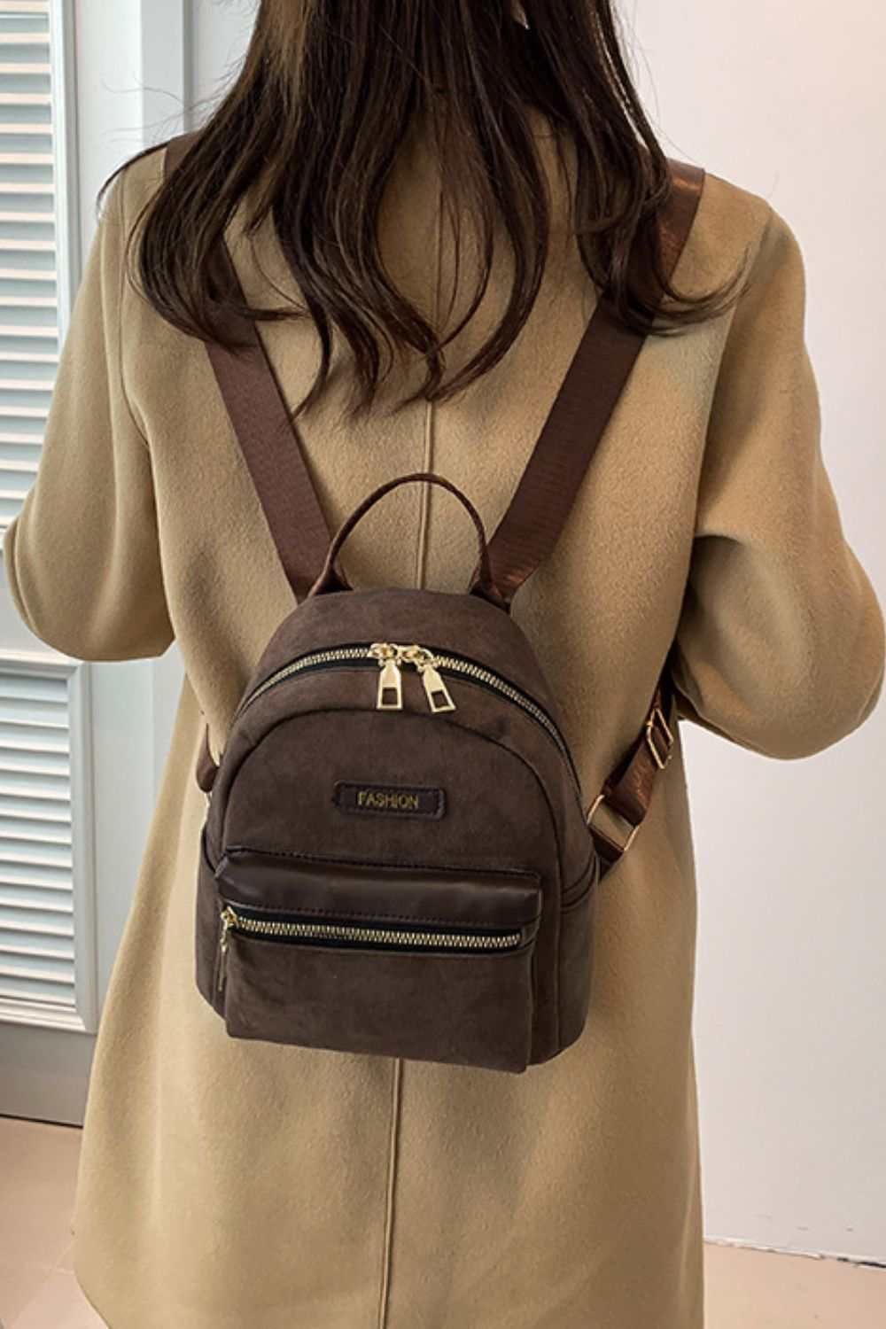 Small suede adjustable strap backpack bag in brown, worn by a person.