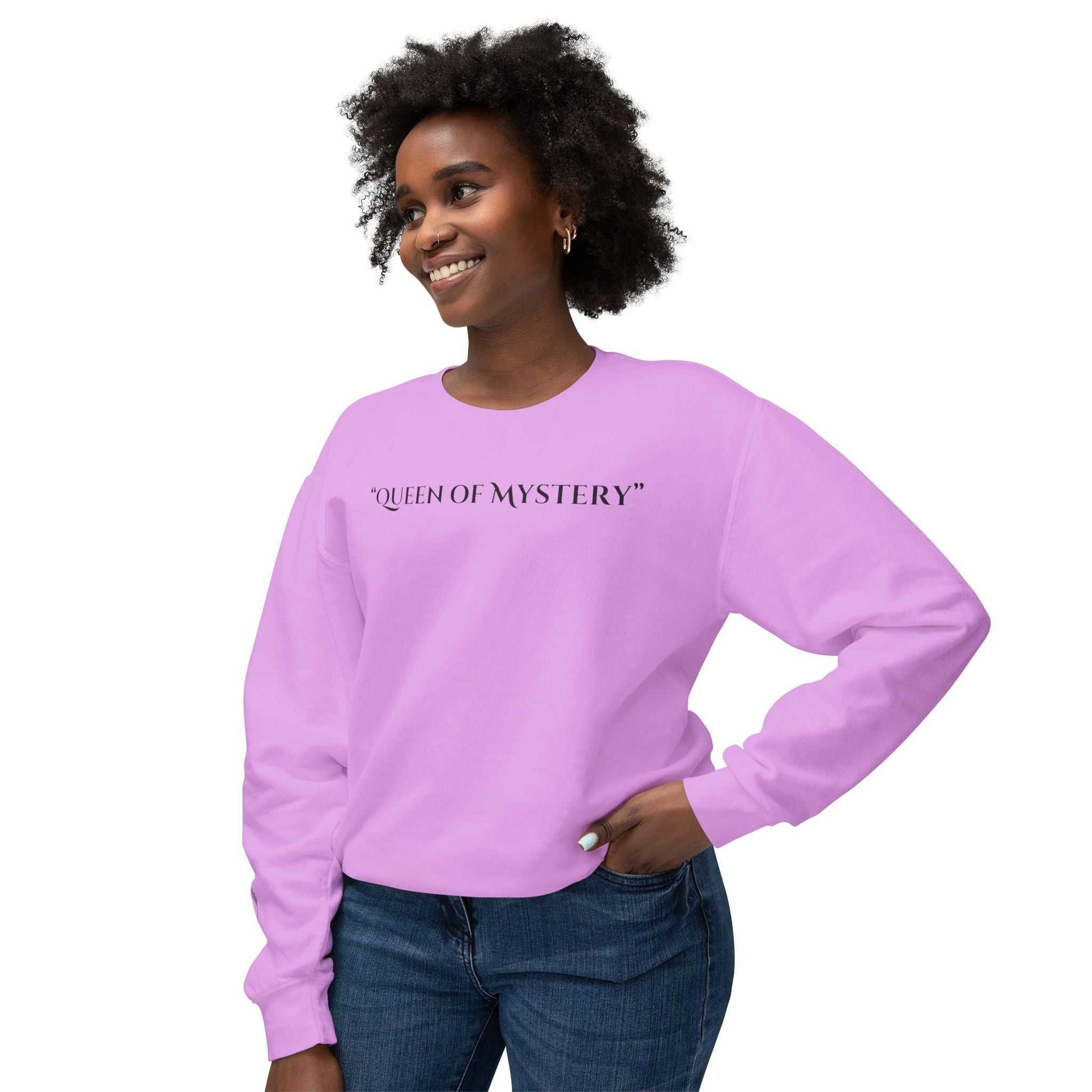 Woman wearing Queens Mystery Sweatshirt in pink with "Queen of Mystery" text.