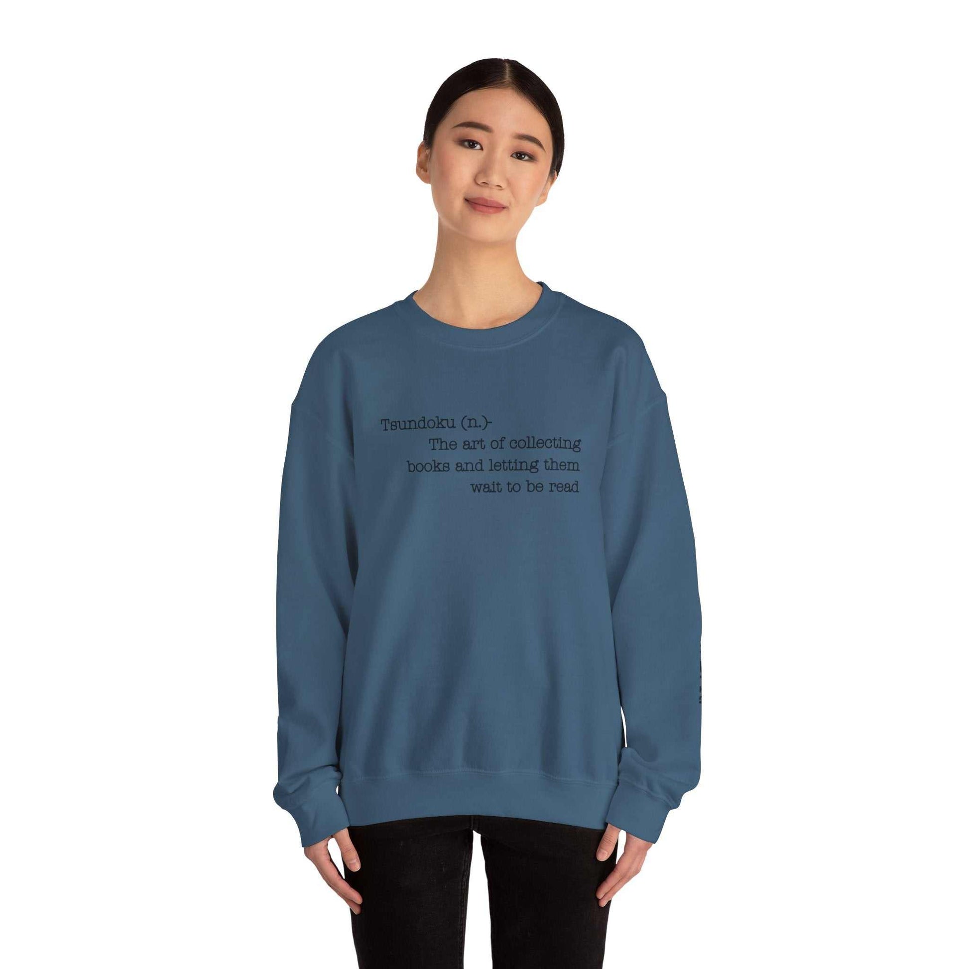 T. B. R. Tsundoku crewneck sweatshirt for book lovers, featuring definition of Tsundoku, cozy cotton-poly blend, model wearing blue.