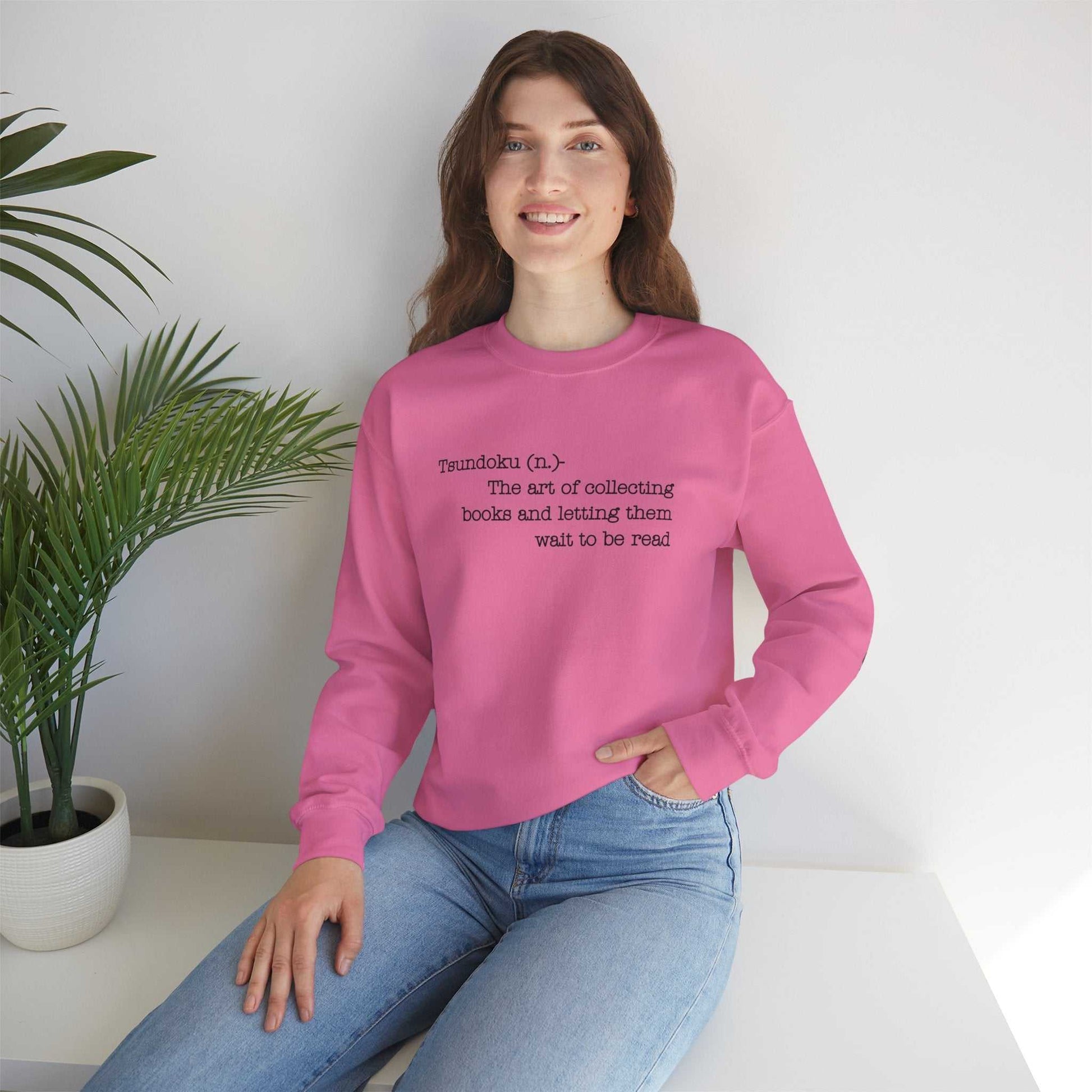 Pink crewneck sweatshirt with "Tsundoku" definition printed on front, ideal for book lovers.