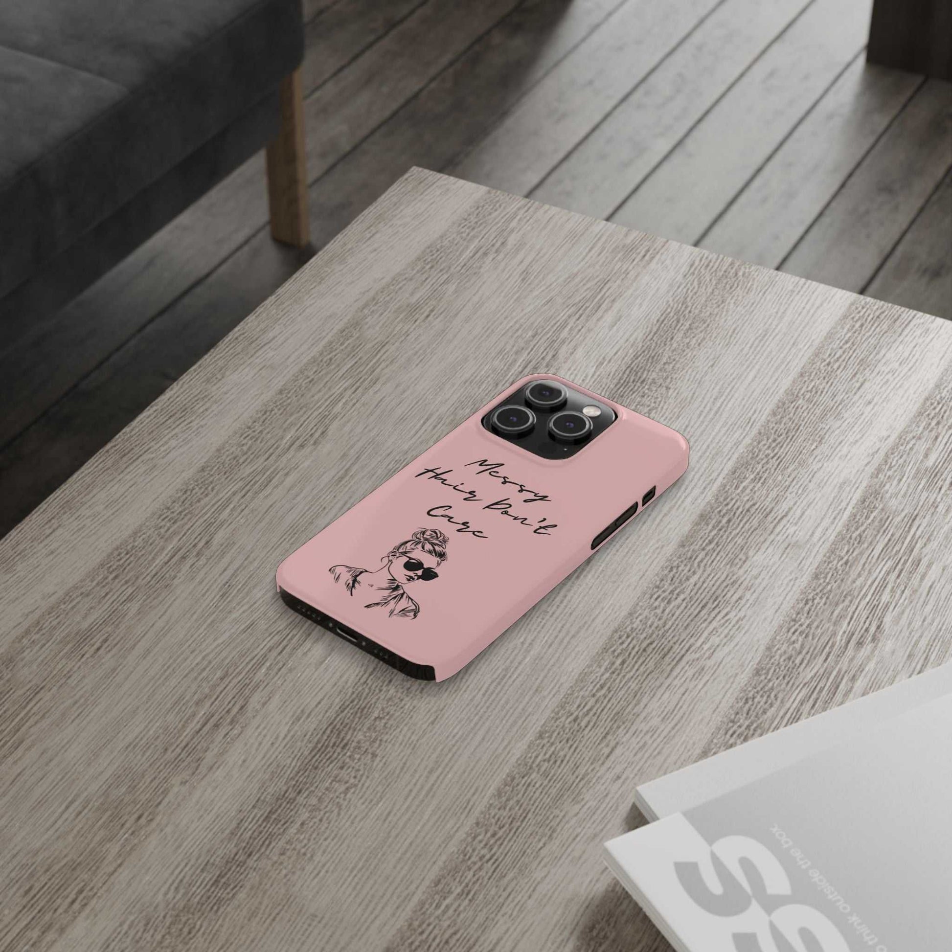 Baby pink phone case featuring 'Messy Hair, Don't Care' design with a girl in sunglasses on a wooden table.