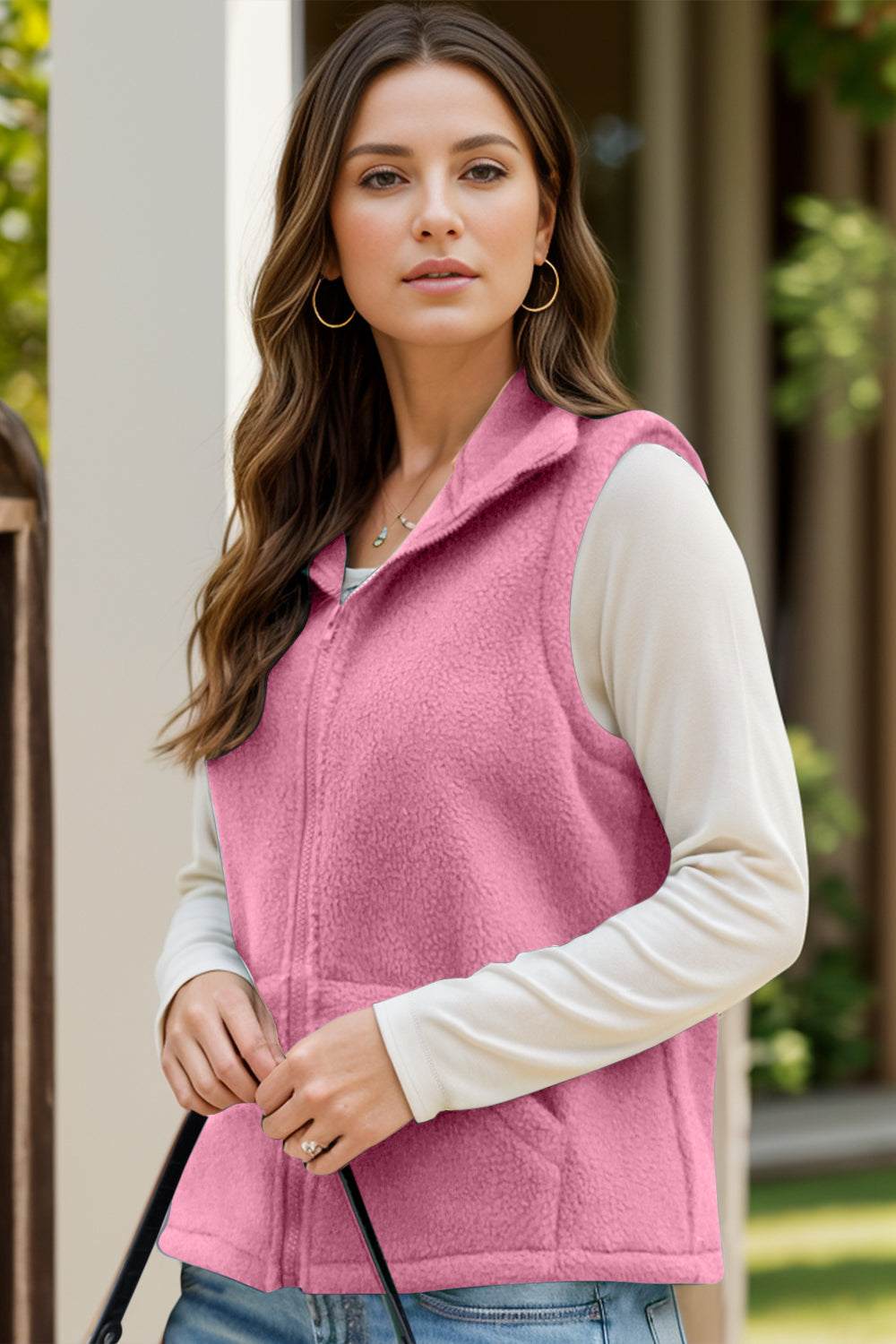 Woman wearing a pink zip-up vest coat with pockets, featuring polyester and spandex material.