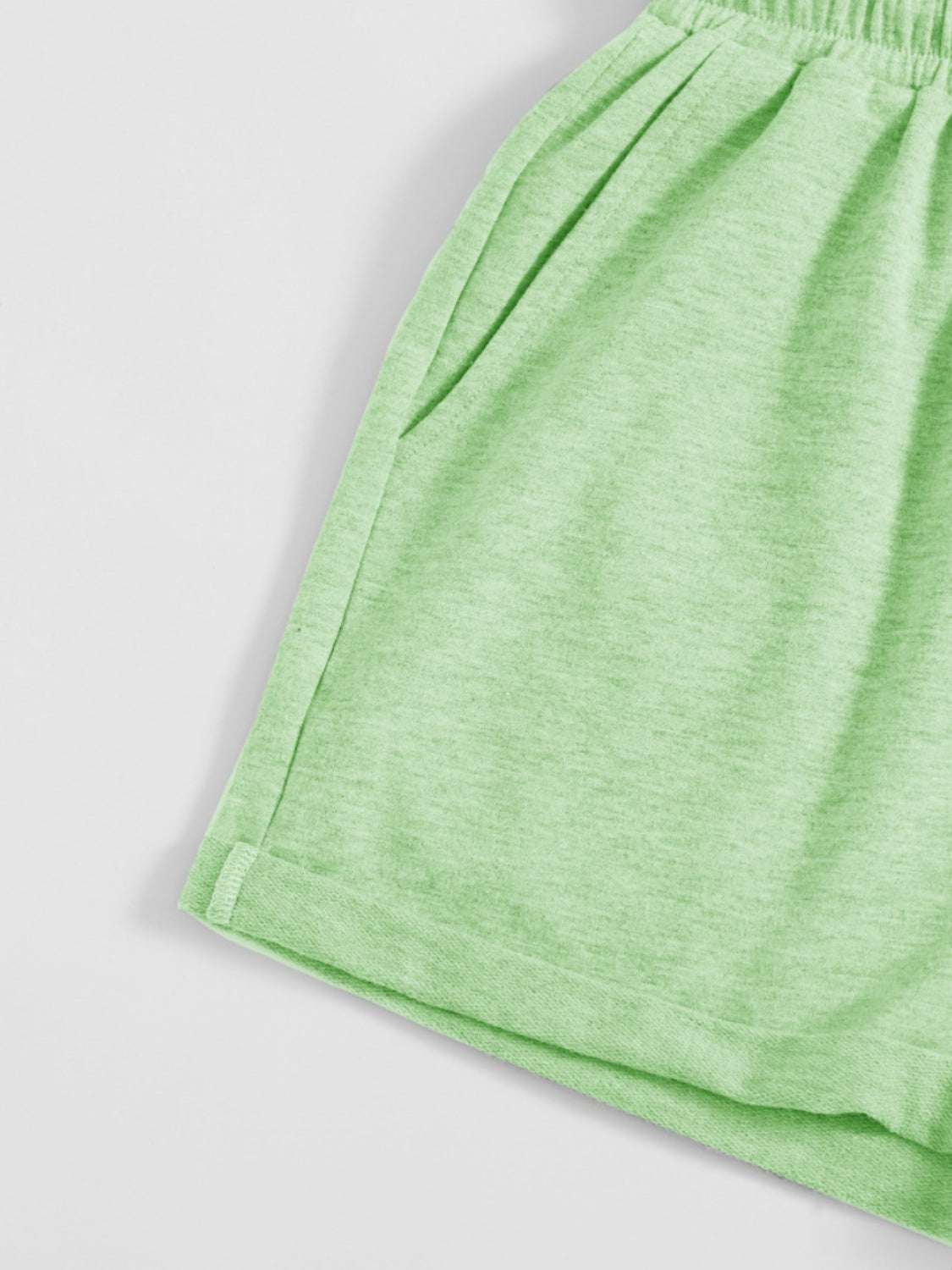 Green drawstring pocketed elastic waist shorts made of polyester.