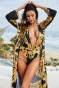 Printed plunge one-piece and cover-up swim set on beach.