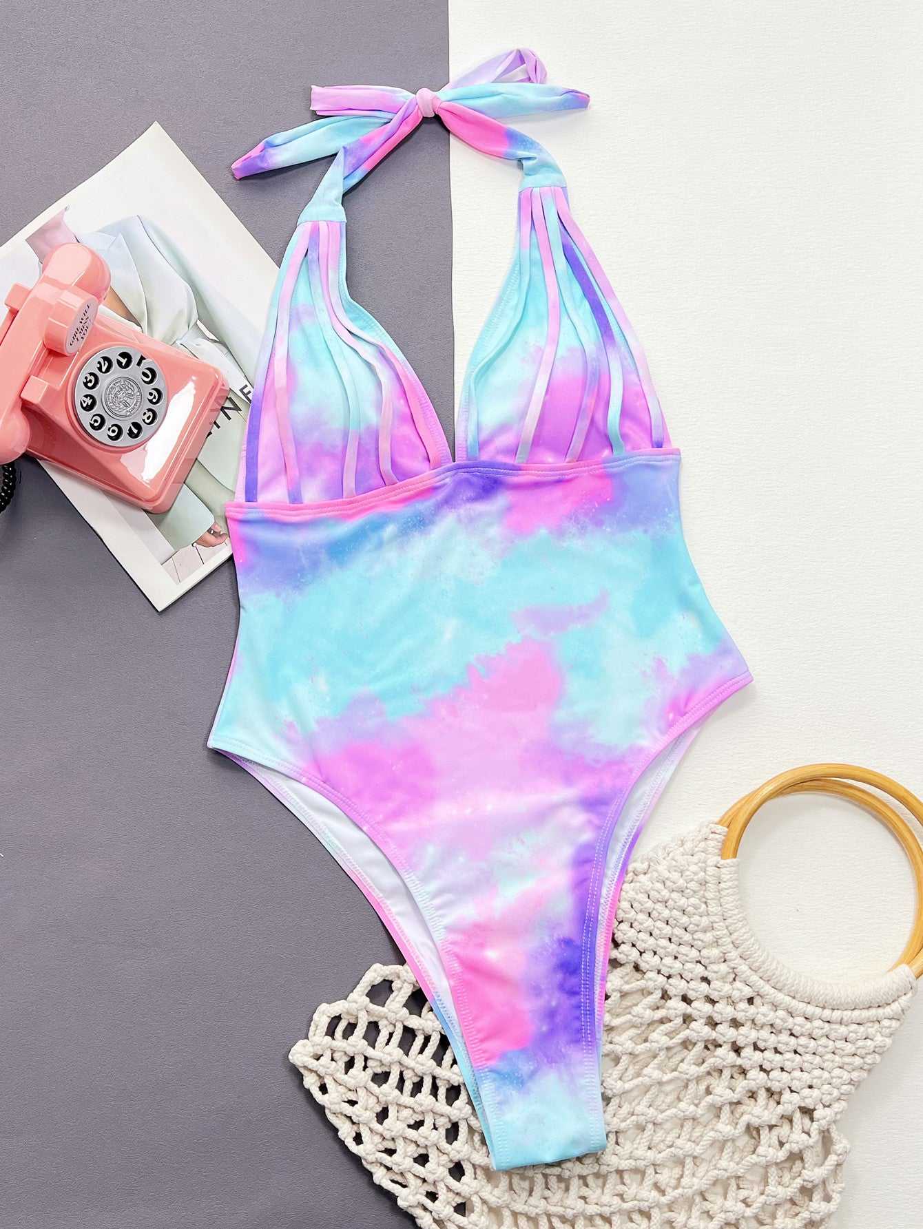 Tie-dye halter neck one-piece swimsuit with removable padding and no underwire, featuring pink and blue hues.