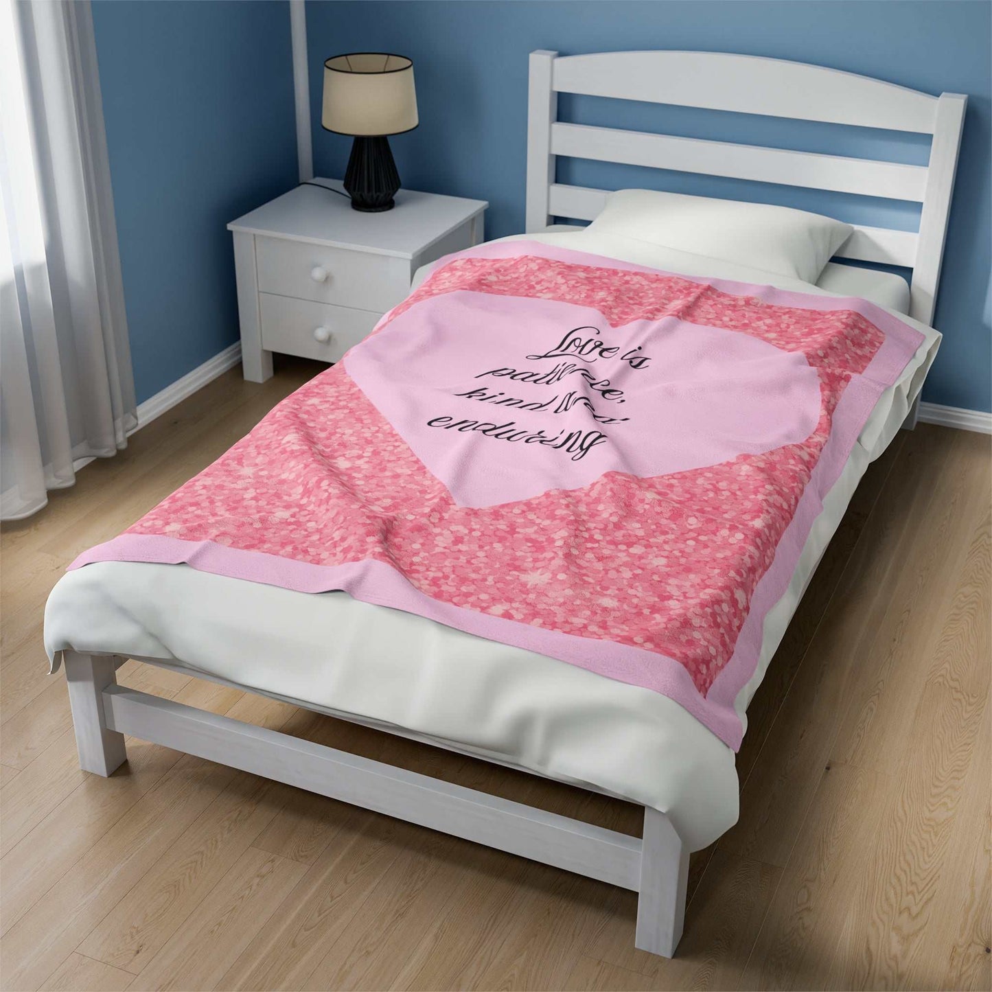 Plush blanket with light pink heart, "Love is patience, kind and enduring" text, surrounded by blush pink glitter design on bed.