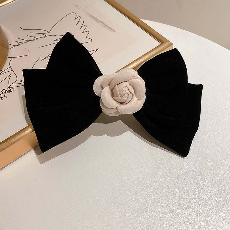 Black hair clip with rose trim bow design made of alloy and polyester.