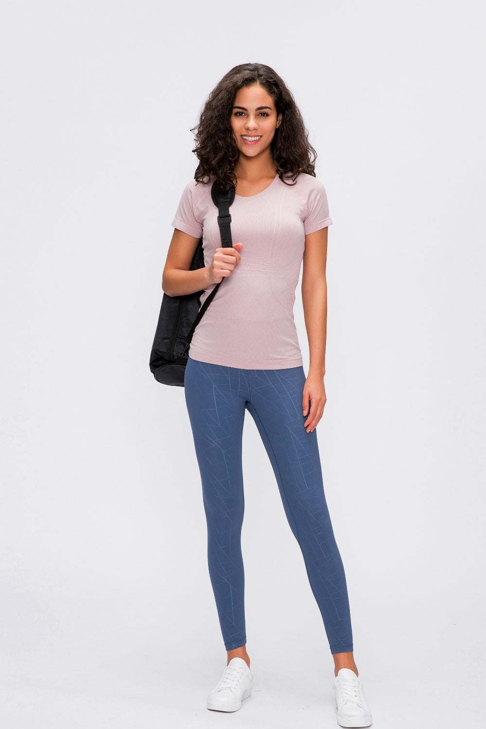 Millennia Round Neck Short Sleeve Active T-Shirt in light pink worn by a model with blue leggings.