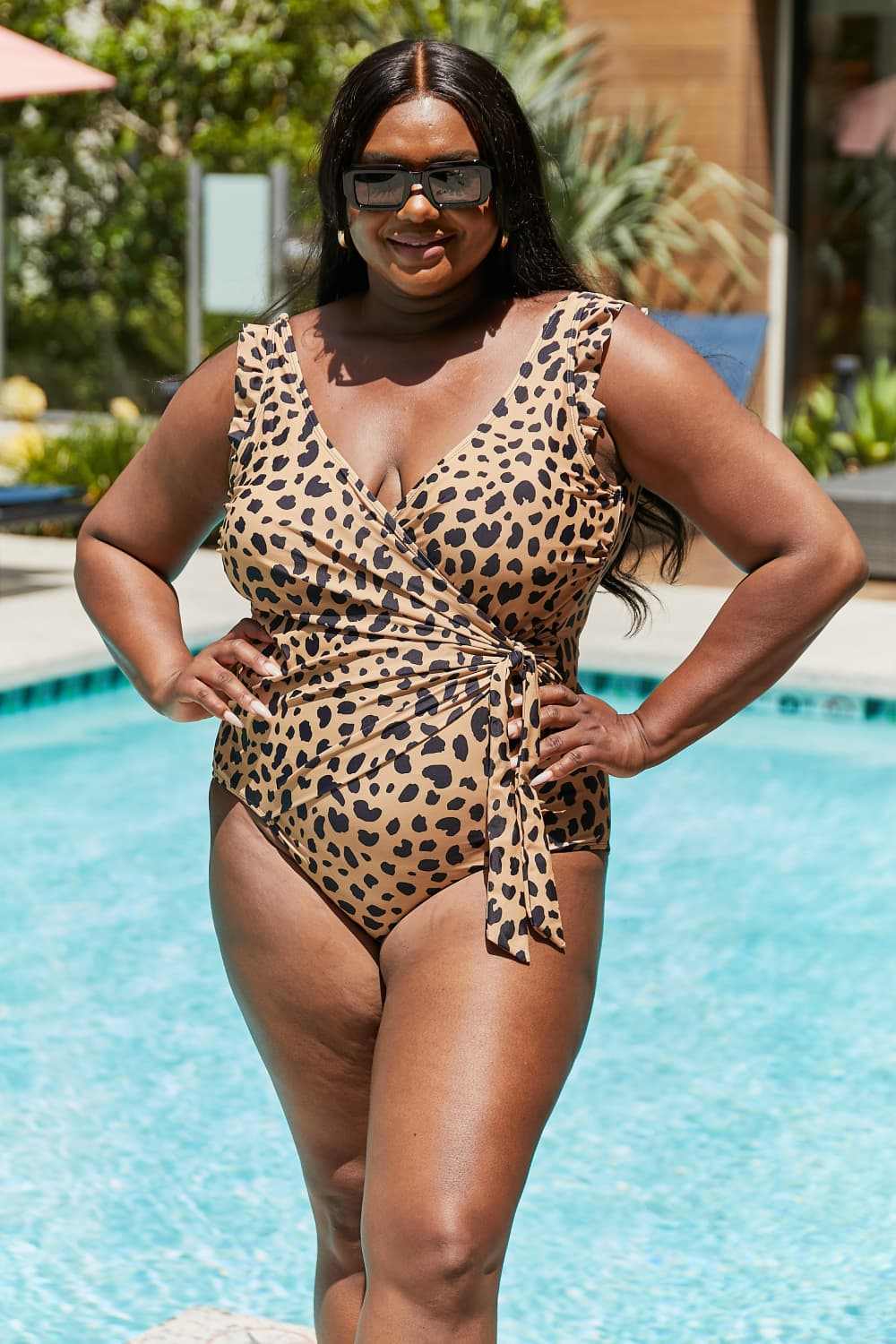 Plus size woman in leopard print one-piece swimsuit with ruffle faux wrap design by Marina West Swim.