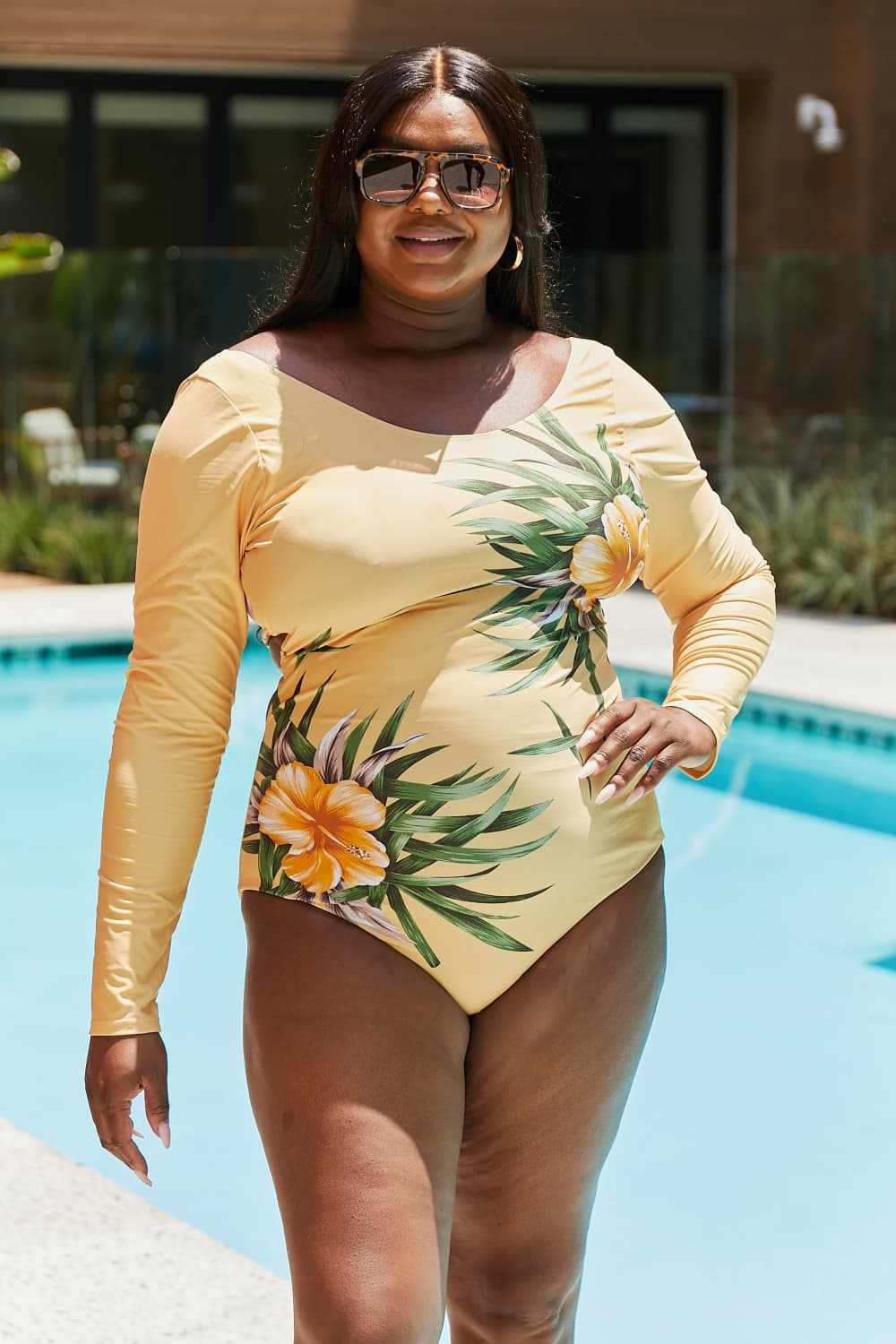 Marina West Swim Cool Down long-sleeve one-piece swimsuit with floral print, providing sun protection and comfort beside a pool.