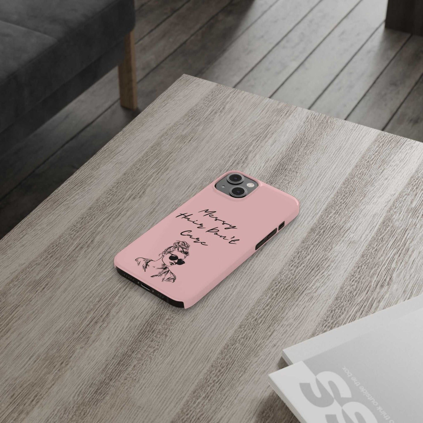 Baby pink phone case with 'Messy Hair, Don't Care' and girl illustration on wooden surface.