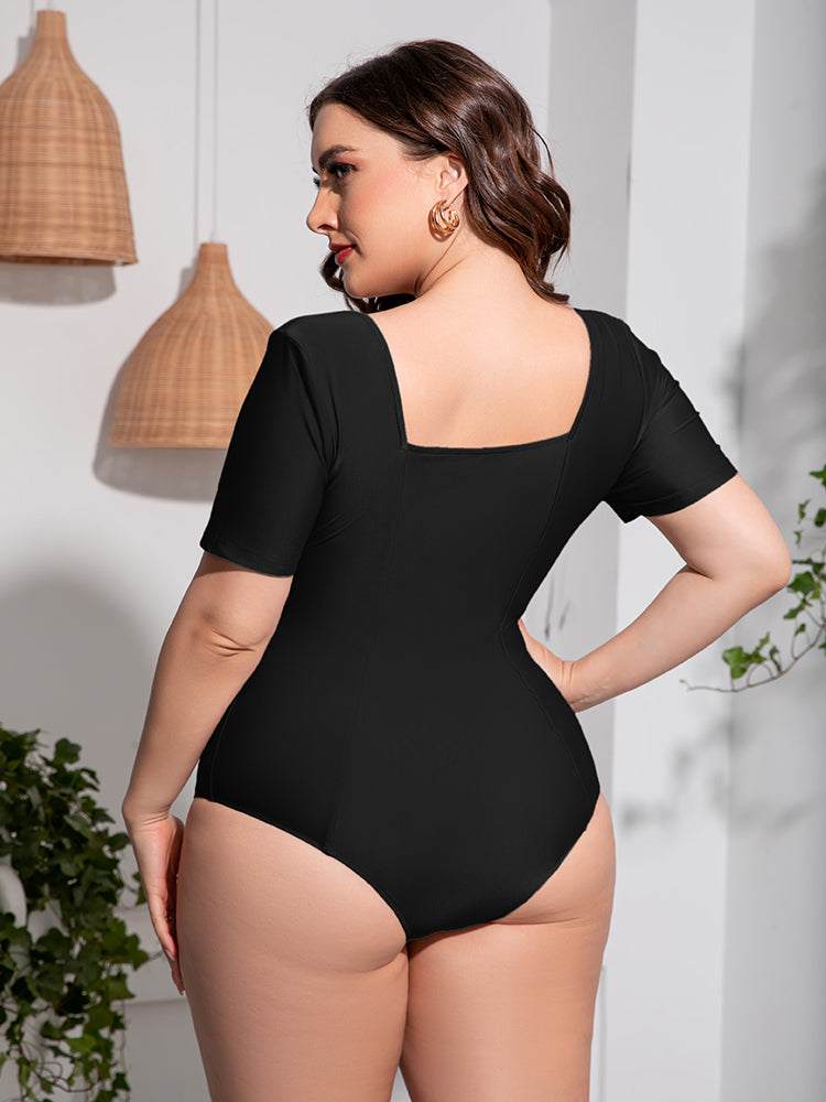 Plus size black one-piece swimsuit with scoop neck and short sleeves.