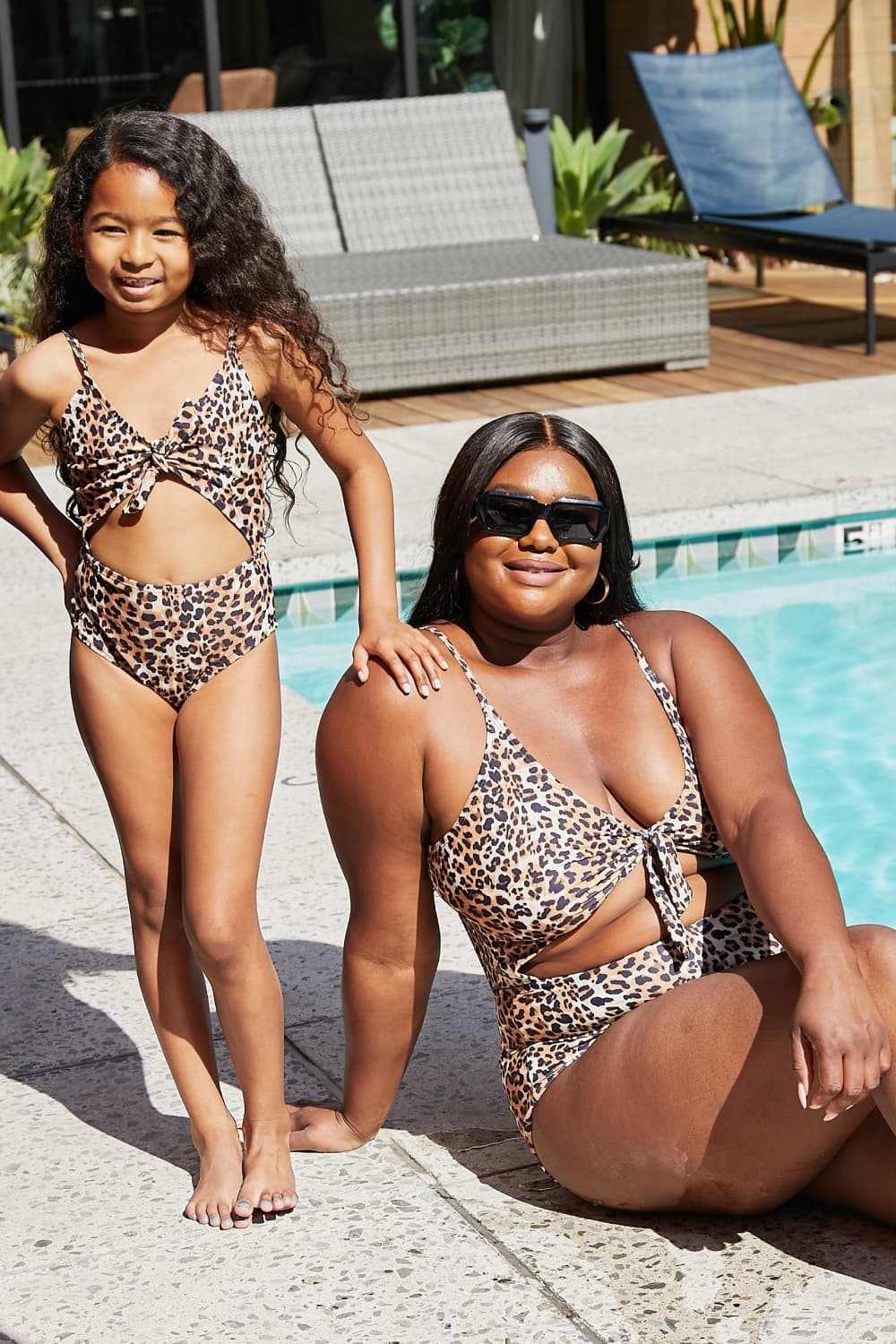 Leopard print cutout one-piece swimsuit by Marina West Swim with plunging neckline, worn by two models poolside.