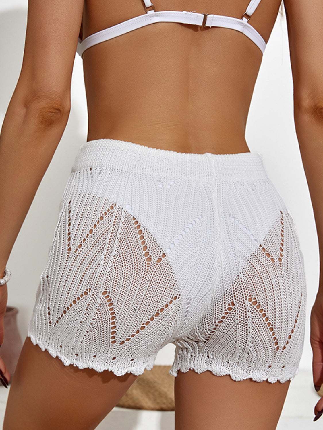 White drawstring cutout swim shorts with stretchy polyester material.