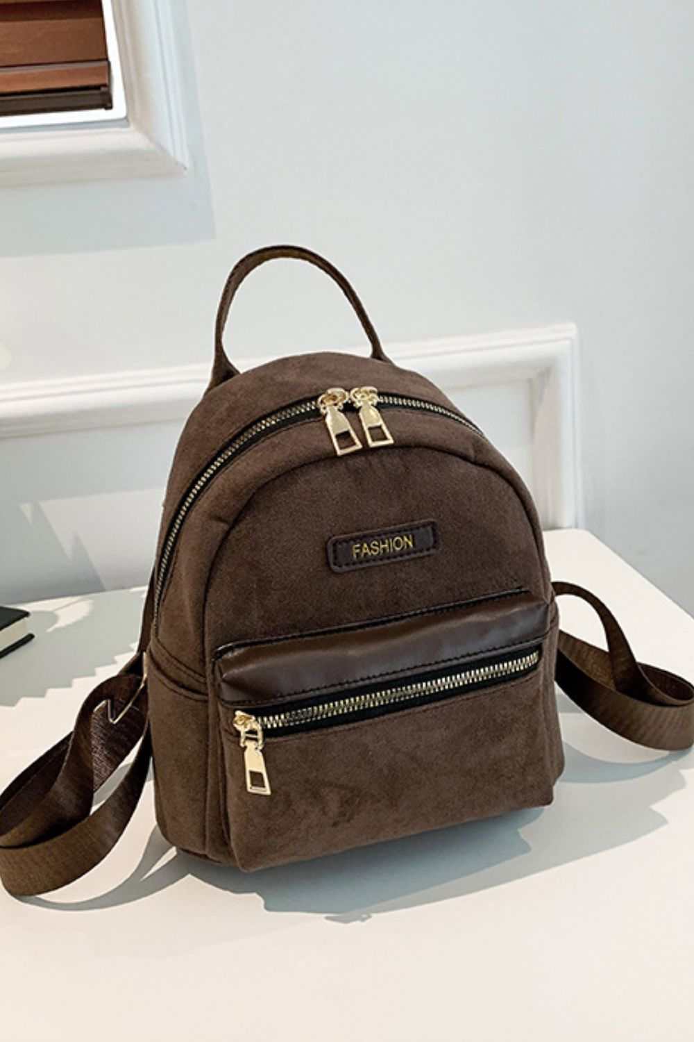 Small suede adjustable strap backpack bag with front zipper pocket.