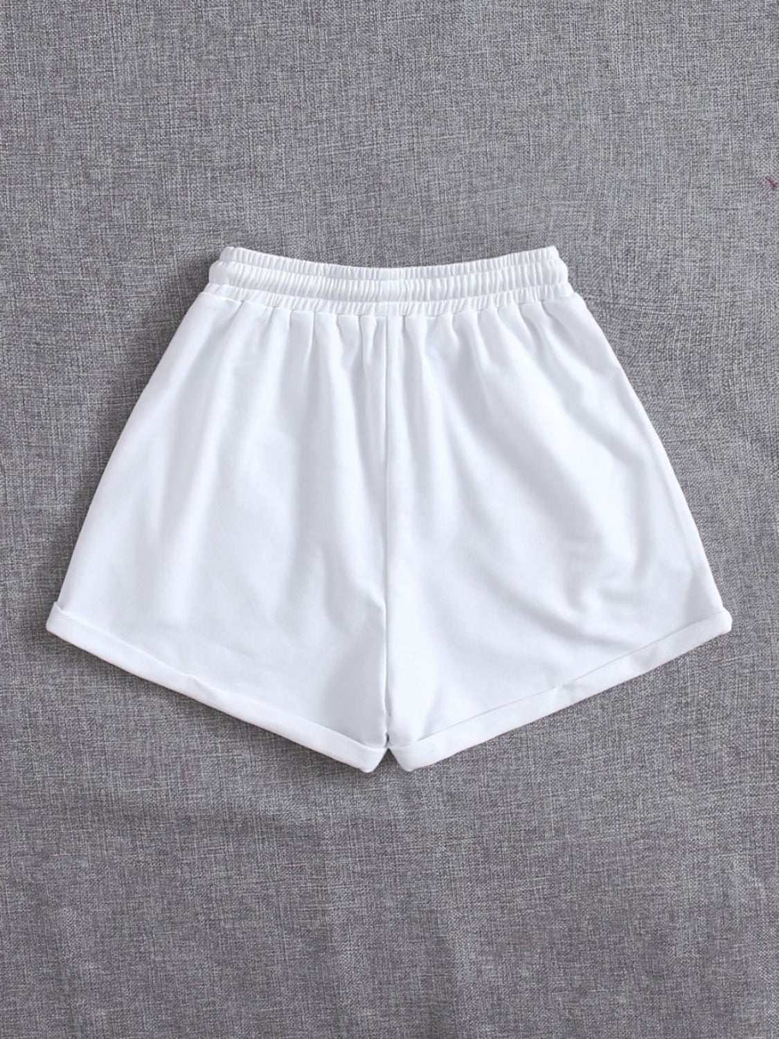 White drawstring pocketed elastic waist shorts made of polyester.