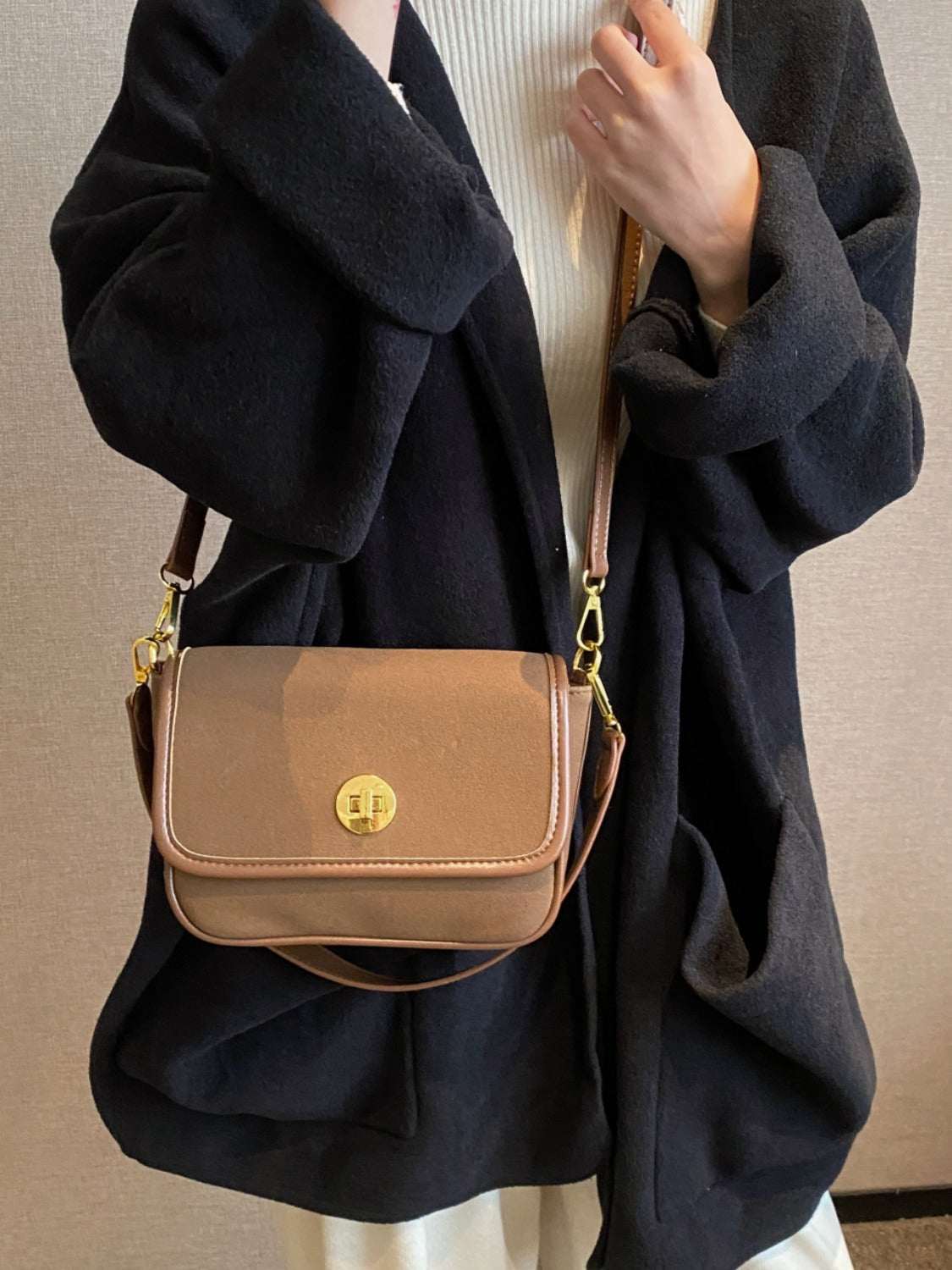 Small PU leather suede twist-lock shoulder bag in brown carried over shoulder.