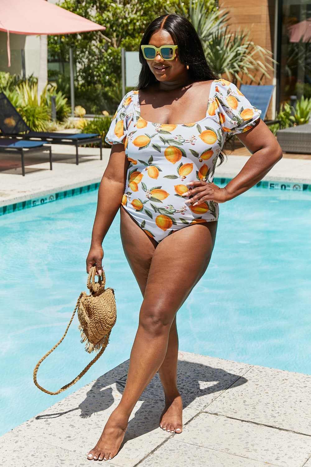 Women's citrus orange puff sleeve one-piece swimsuit by Marina West Swim, featuring printed design and scoop neck, worn by the pool.