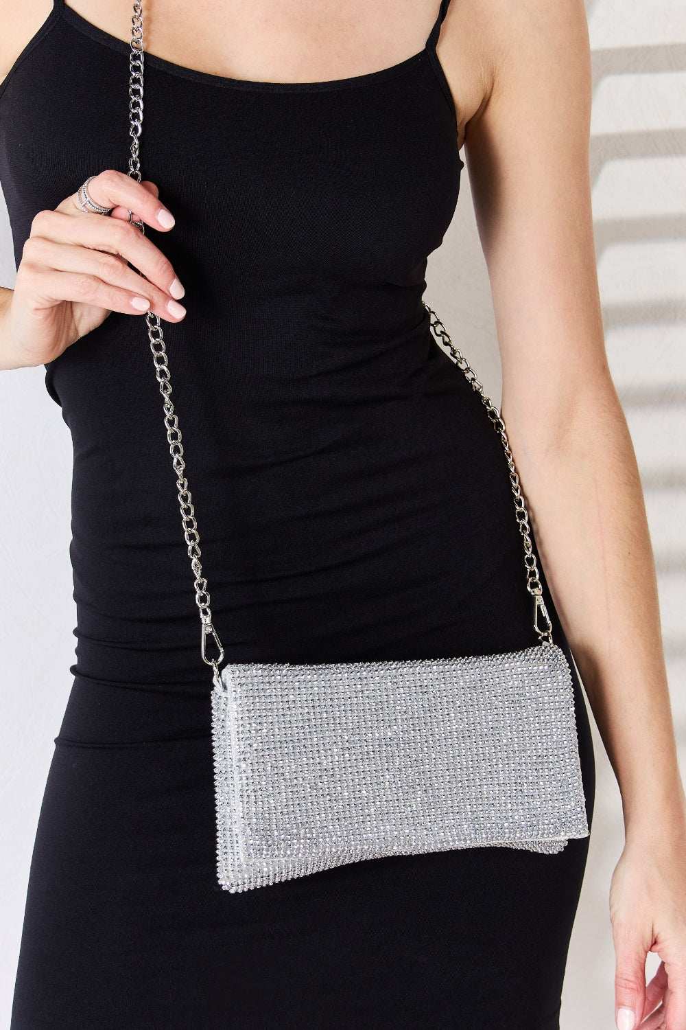 Forever Link Rhinestone Crossbody Bag in silver on model in black dress, featuring dazzling rhinestones and a chain strap.