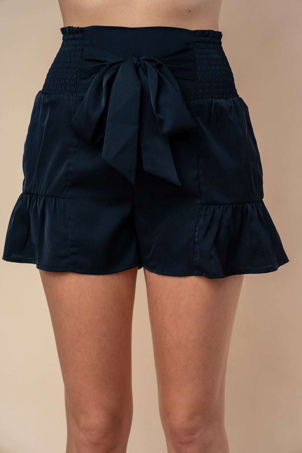 White Birch high-waisted smocked shorts with front tie and ruffle hem.