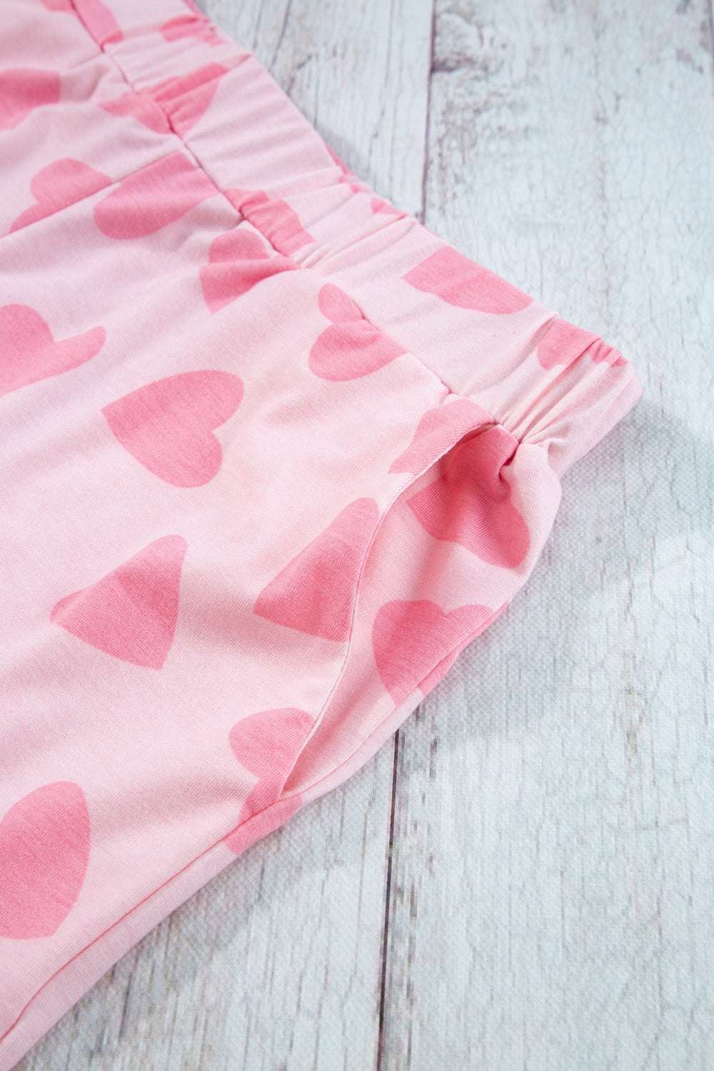 Heart print round neck top and shorts lounge set on wooden background.