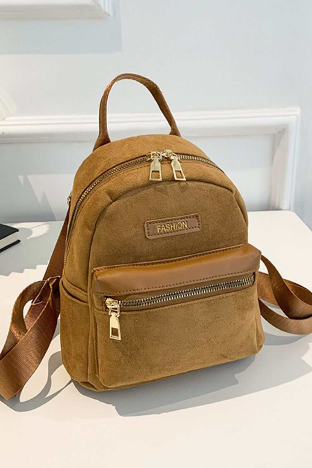 Small suede adjustable strap backpack bag on display.