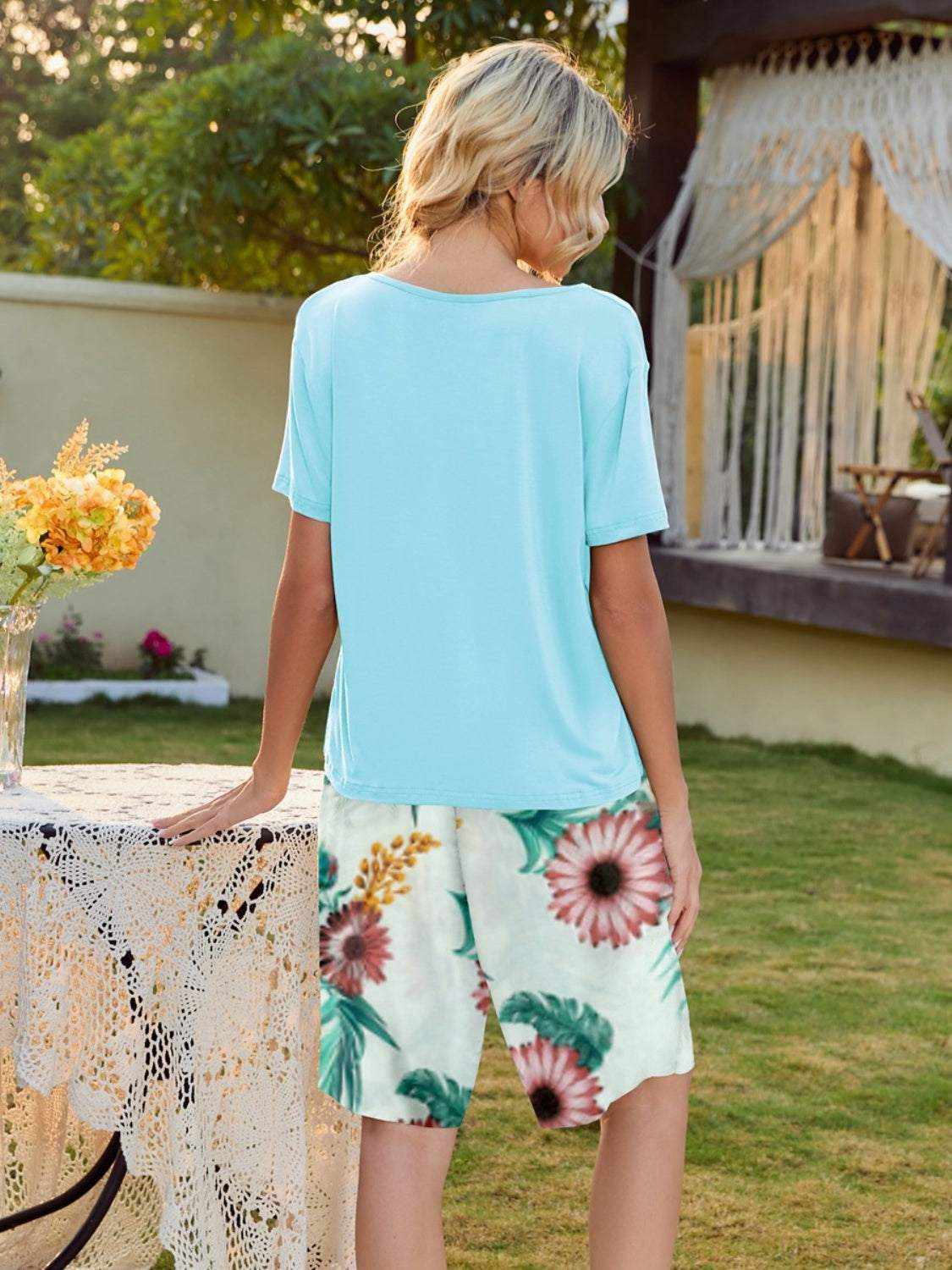 Woman wearing short sleeve top and printed shorts lounge set outdoors.