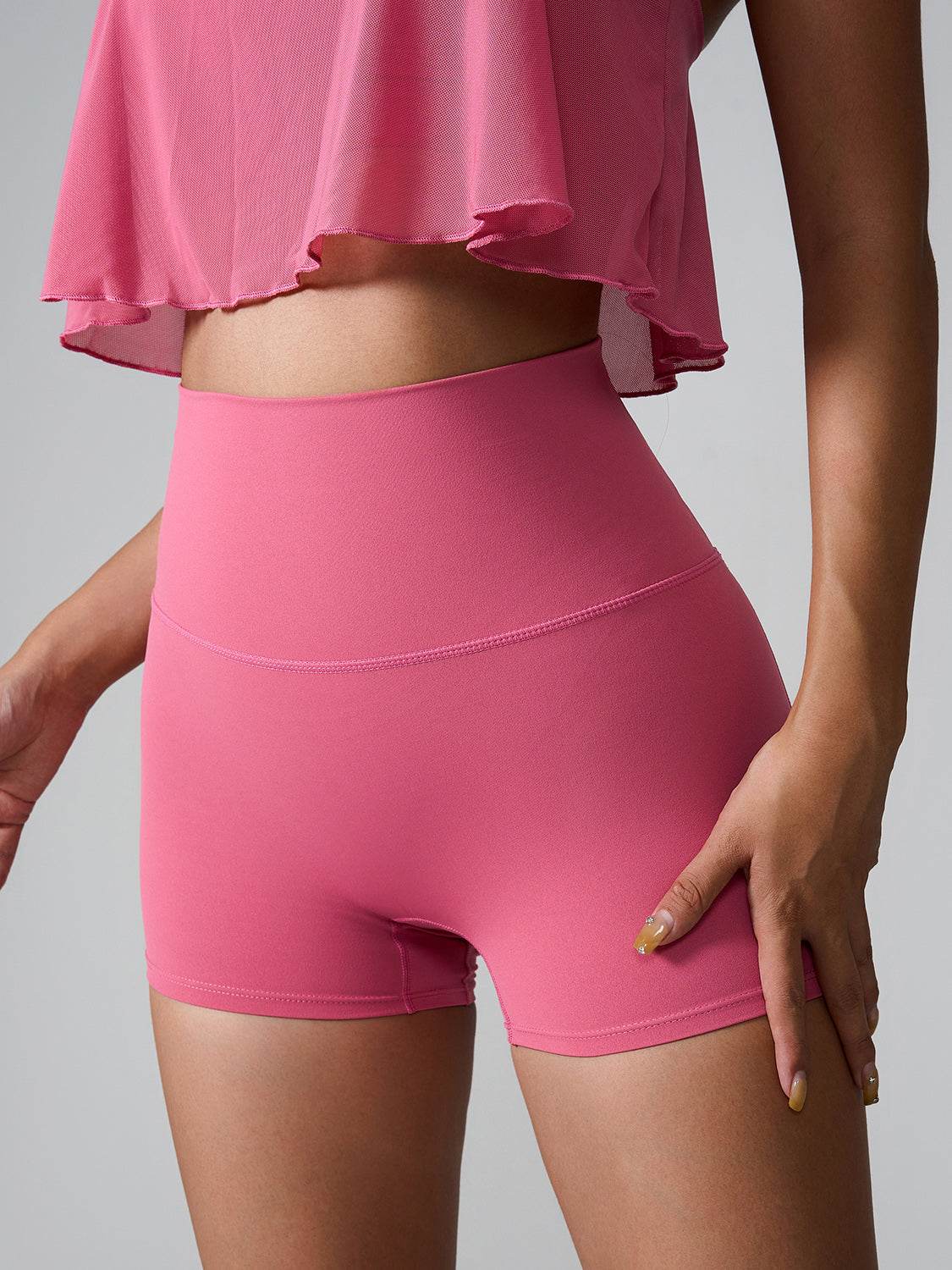 Pink high waist active shorts with pockets, made from stretchy nylon and spandex, suitable for workout.