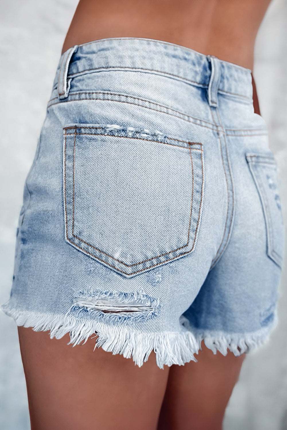 Distressed raw hem denim shorts with back pocket detail.