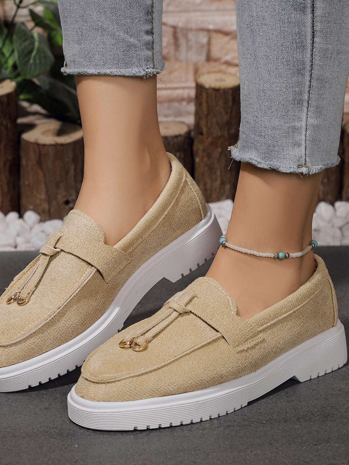 Beige round toe flat slip-ons made of rubber and polyester.