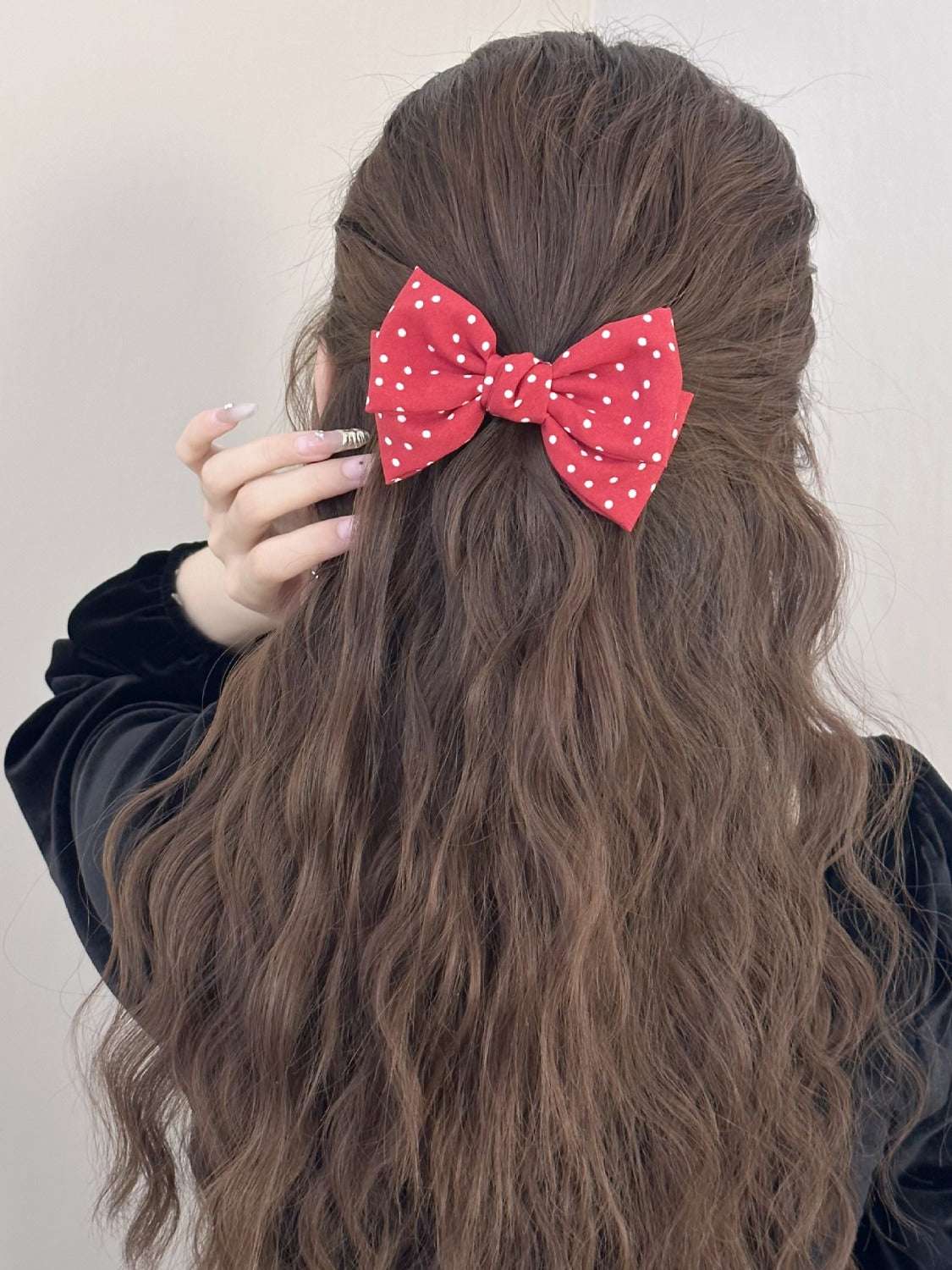 Red polka dot bow hair clip on long brown hair.