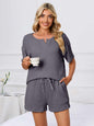 Notched short sleeve and shorts lounge set in dark gray worn by woman holding a cup.