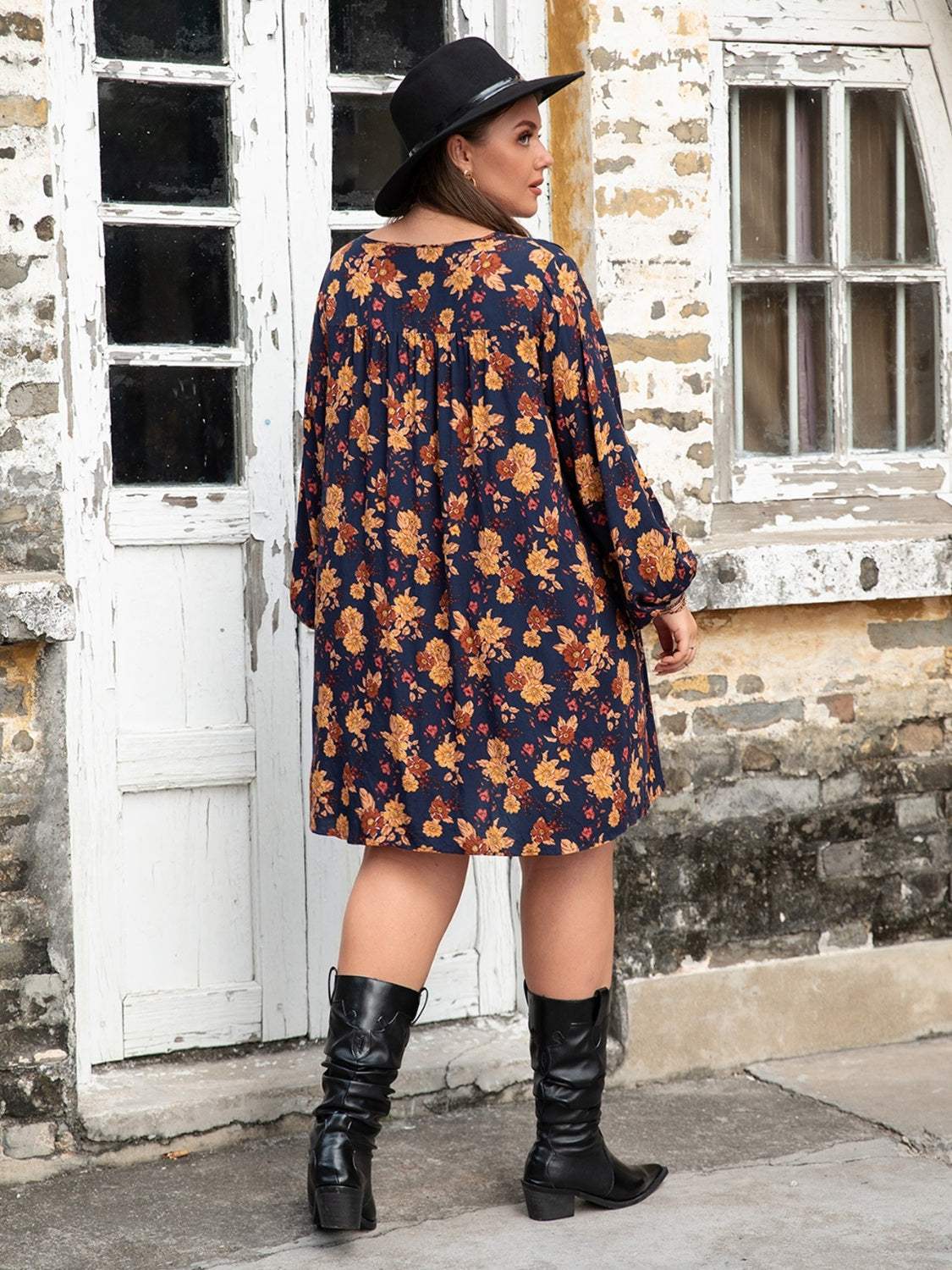 Plus size floral V-neck balloon sleeve dress in blue with orange flowers, shown worn by a woman standing outside near a vintage door.