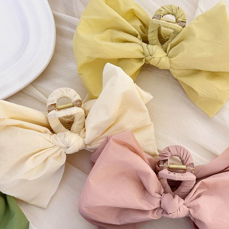 Bow hair claw clip in polyester, 5.1 inches long, available in pastel colors.