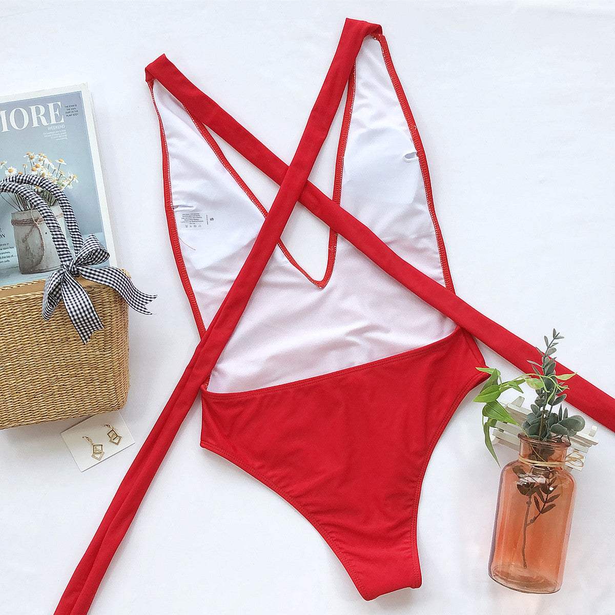 Halter neck deep V tied one-piece swimsuit in red, featuring crisscross design and removable padding.