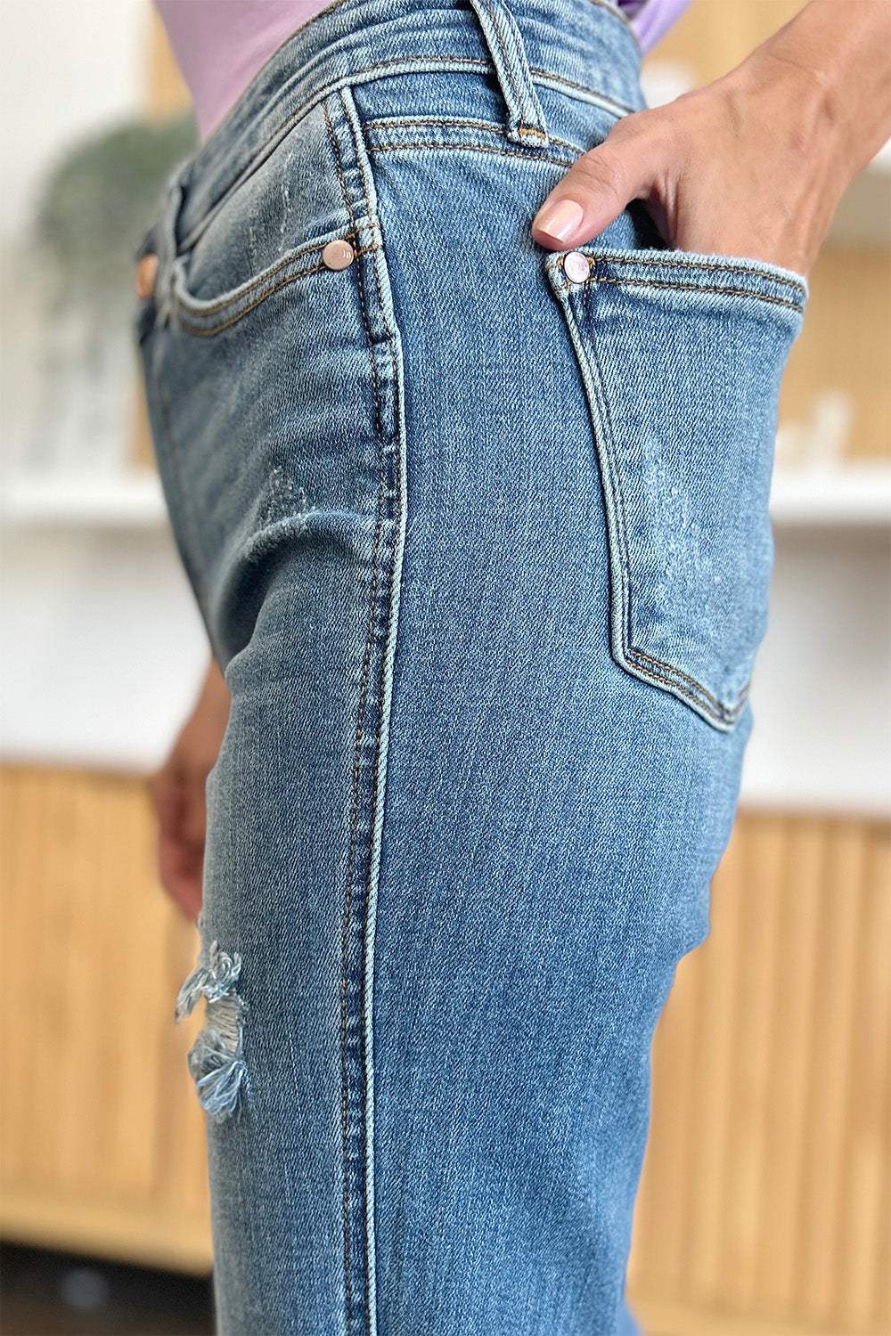 Judy Blue full size distressed raw hem bootcut jeans, close-up side view.