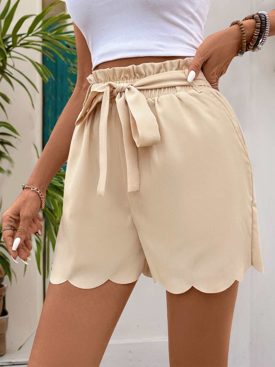 Perfee Frill Tied Shorts with Pockets in beige, featuring a tie waist and scalloped hem, made from 100% polyester.