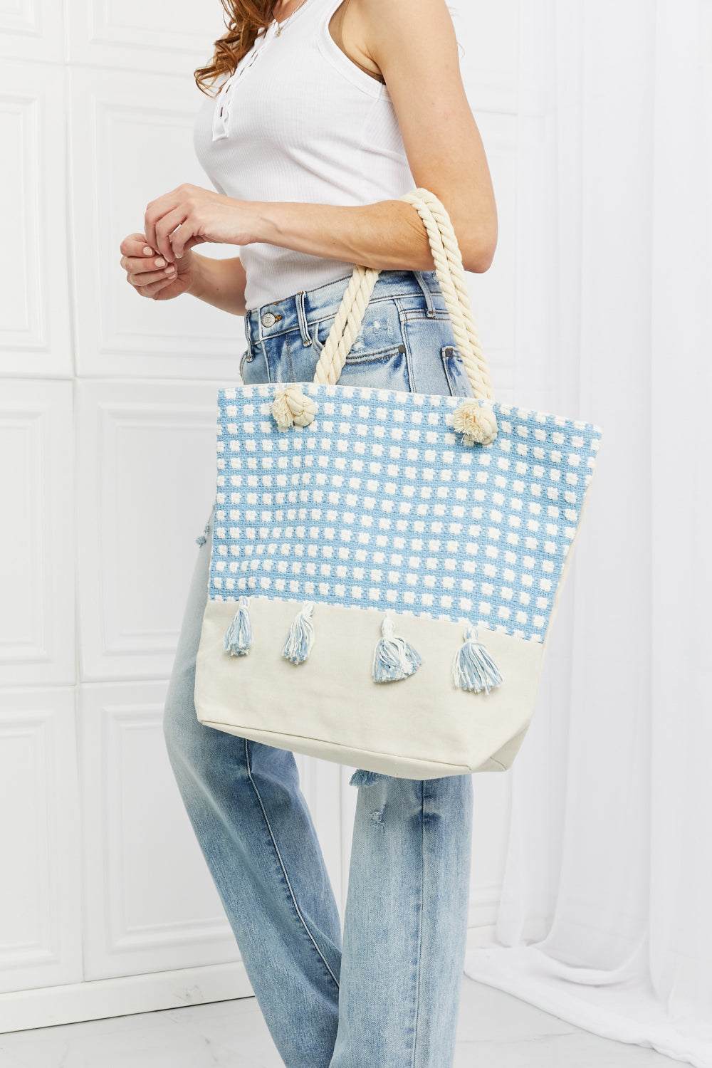 Justin Taylor Picnic Date Tassel Tote Bag with plaid pattern and tassel accents, featuring sturdy rope handles.