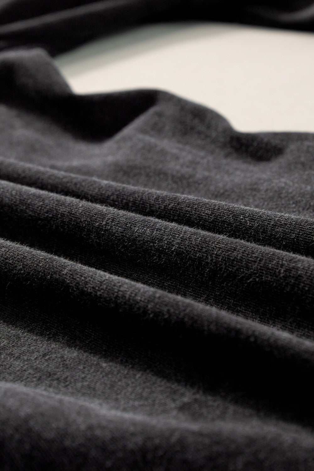 Close-up view of black cotton fabric for plus size drawstring wide leg pants.