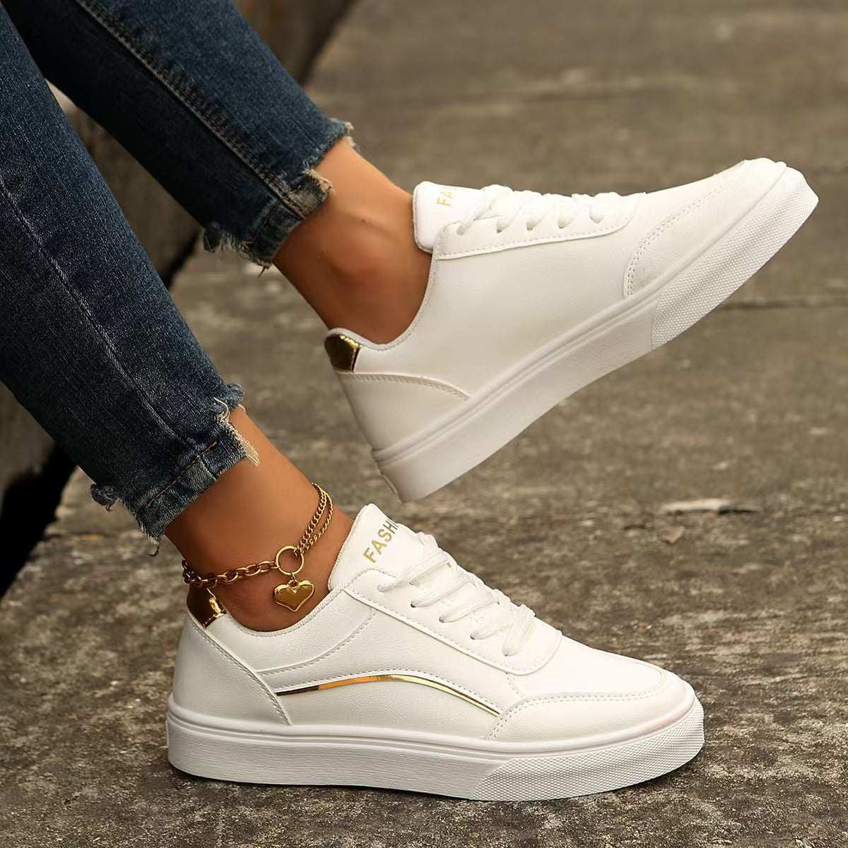 PU leather round toe flat sneakers in white worn with casual jeans.