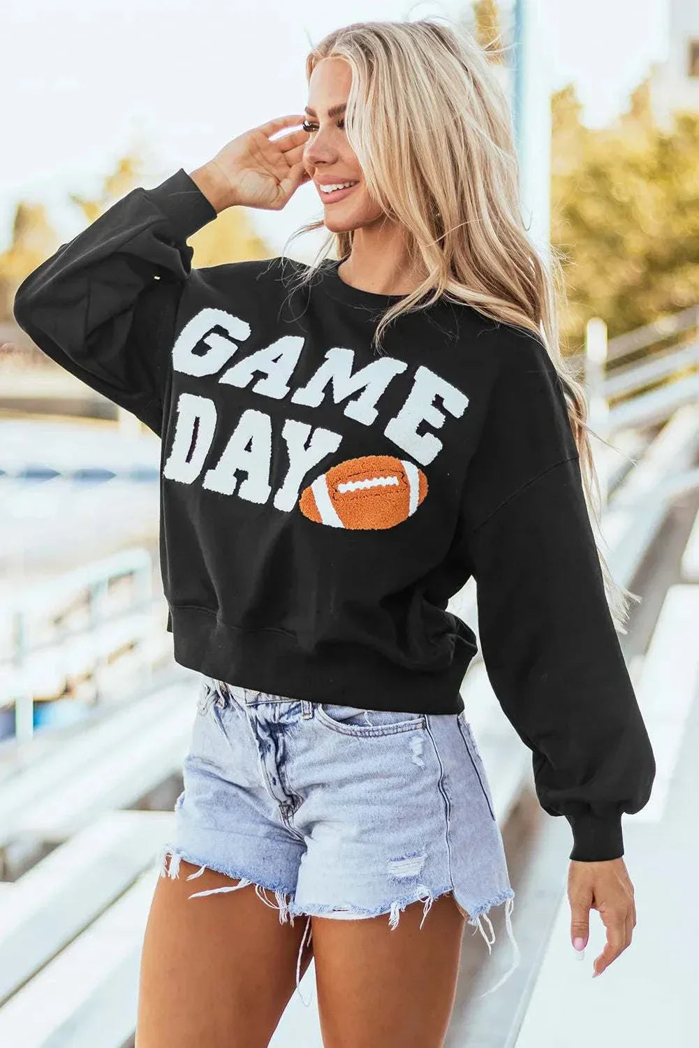 GAME DAY Round Neck Long Sleeve Sweatshirt in black with football graphic, styled with denim shorts.