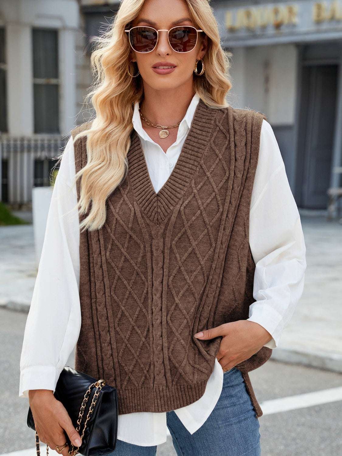 Cable knit V-neck sweater vest in brown, styled over a white shirt, with a casual street look.