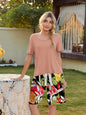 Women's short sleeve top and printed shorts lounge set in a garden setting.