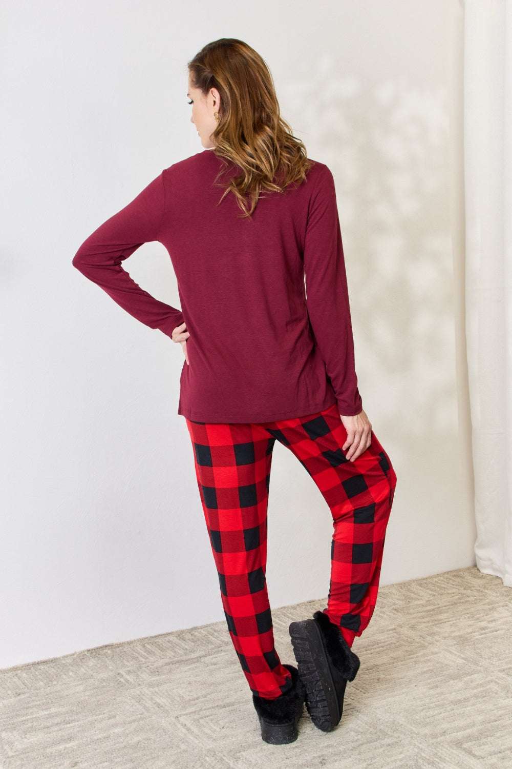 Woman wearing Zenana full-size plaid round neck top and pants pajama set, featuring a burgundy top and red plaid pants.