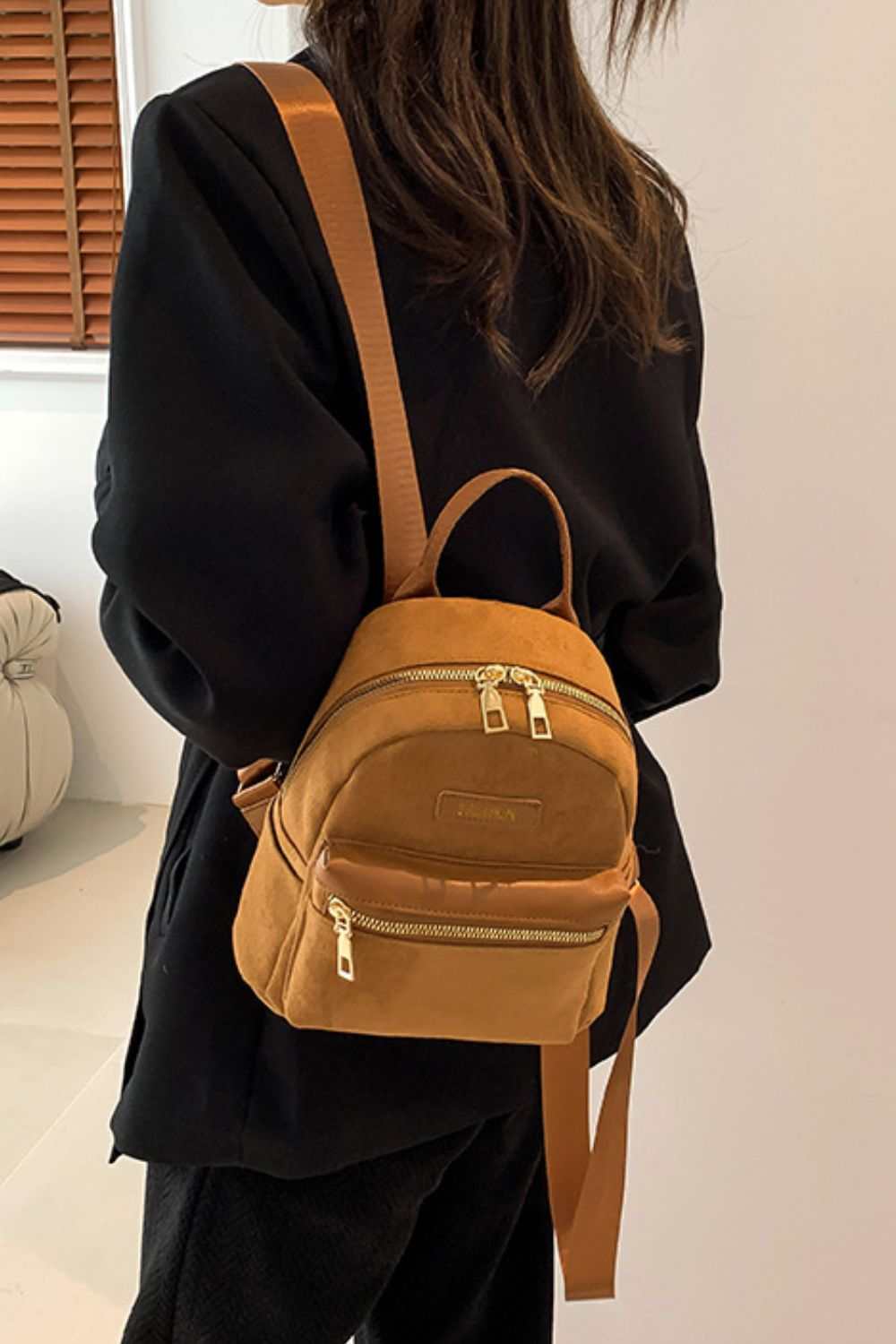 Small suede adjustable strap backpack bag with gold zippers.