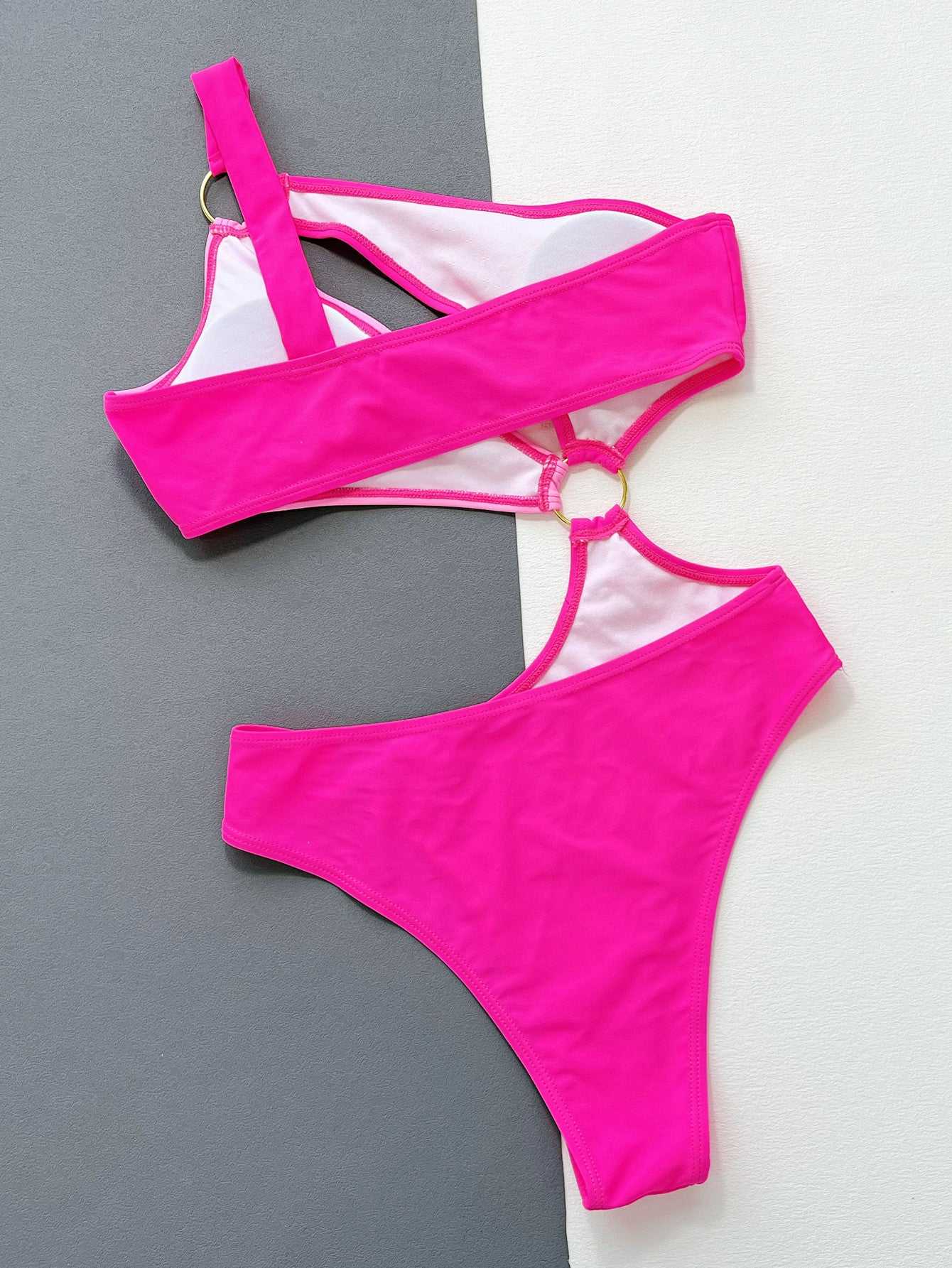 One-shoulder cutout ring detail one-piece swimsuit in bright pink with grommet feature.